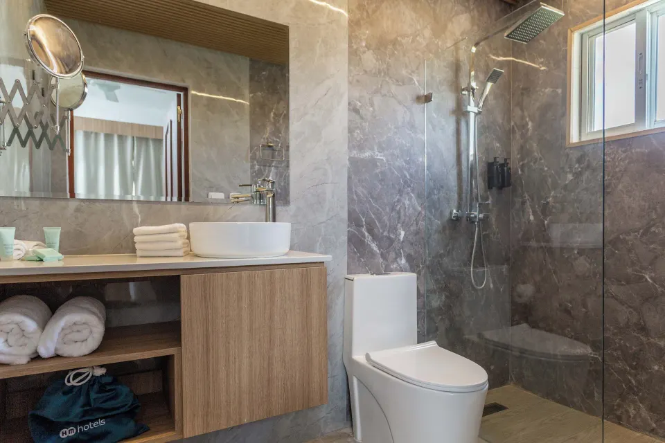Guest bathroom with vessel sink, toilet and glass shower at HM Alma de Bayahibe.