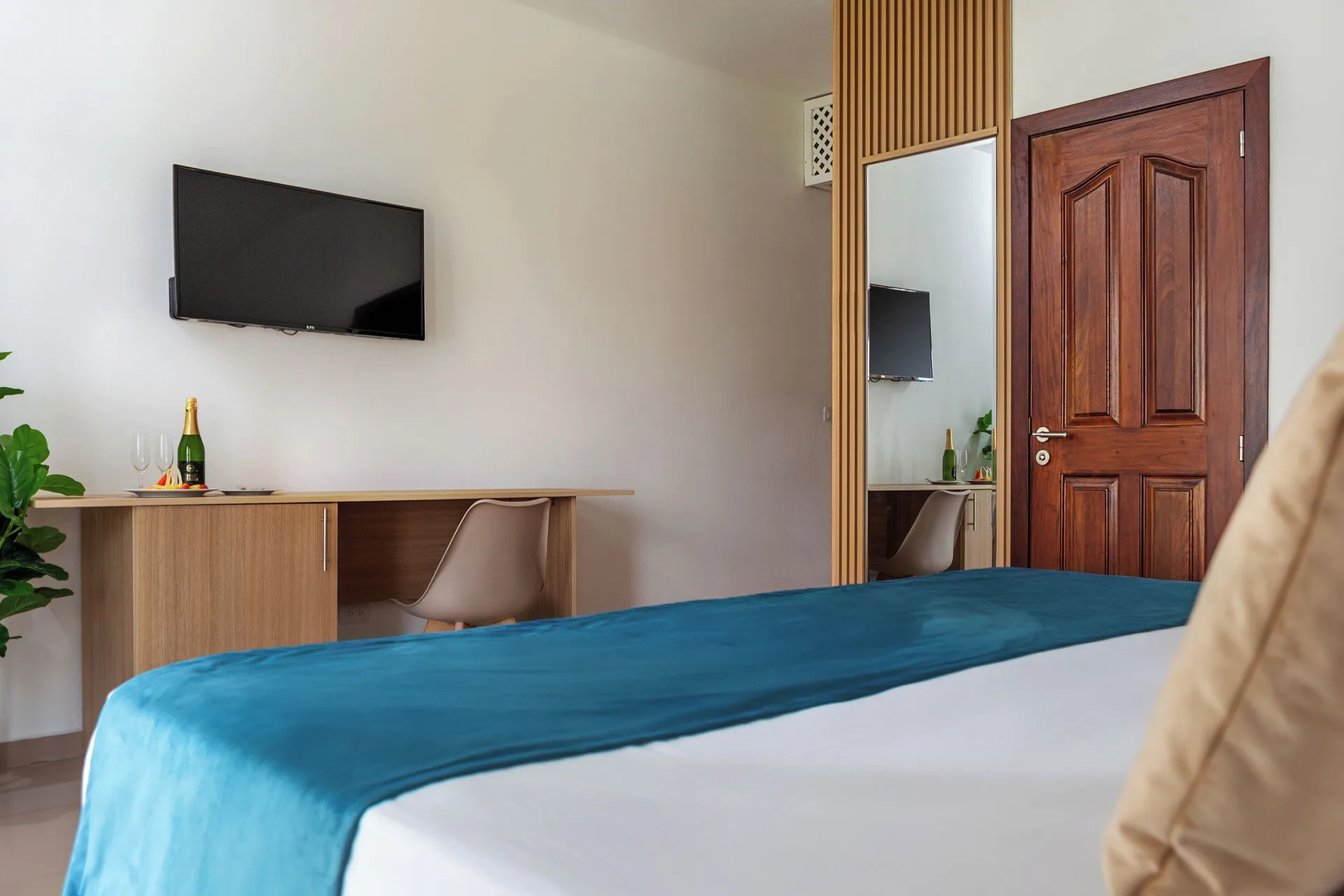 Guest room with bed, wall-mounted TV, desk and mirror at HM Alma de Bayahibe.