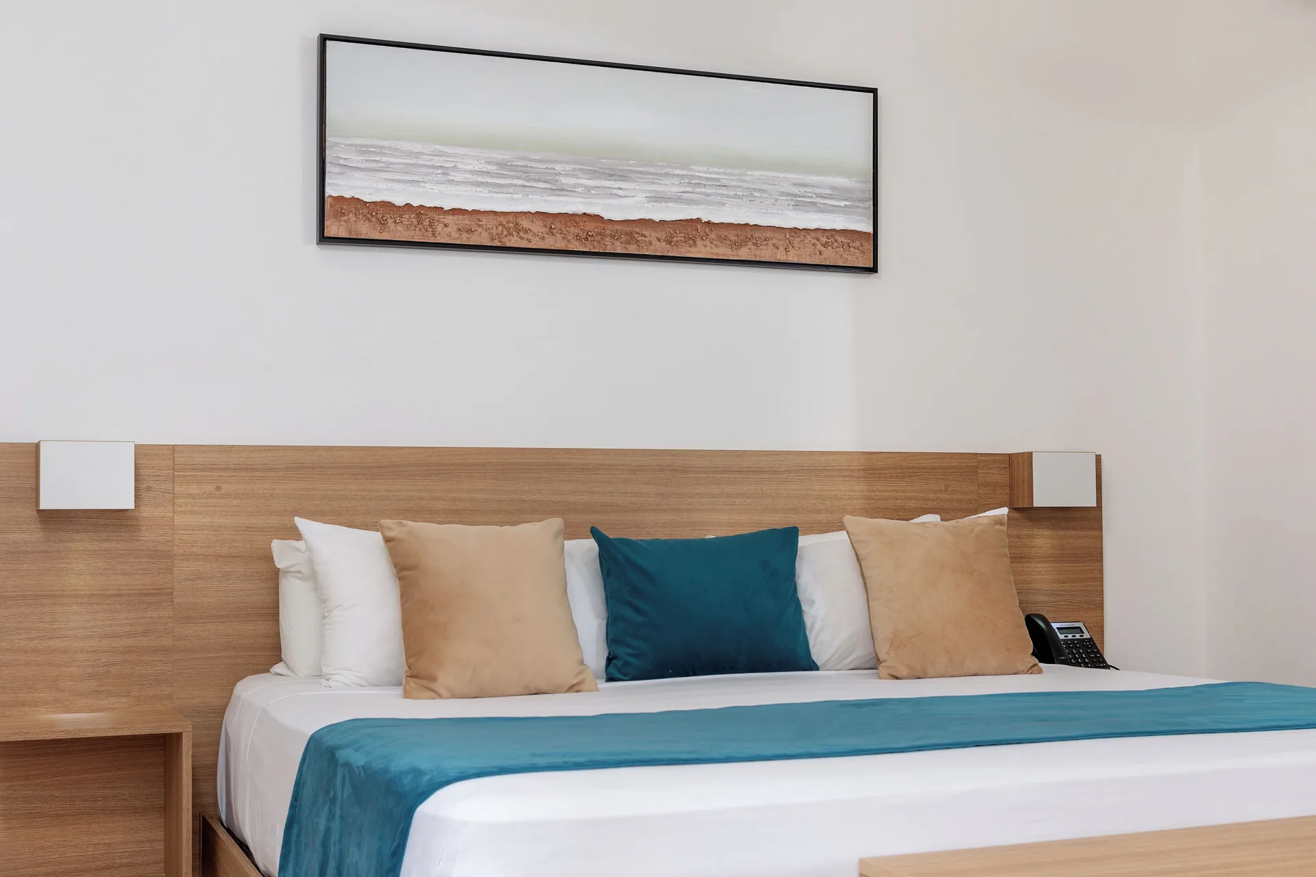 King bed with teal runner, pillows and wall art at HM Alma de Bayahibe.
