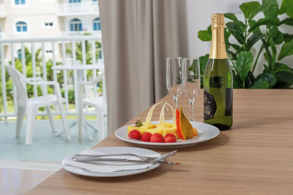 In-room table with fruit plate, sparkling wine and balcony beyond at HM Alma de Bayahibe.