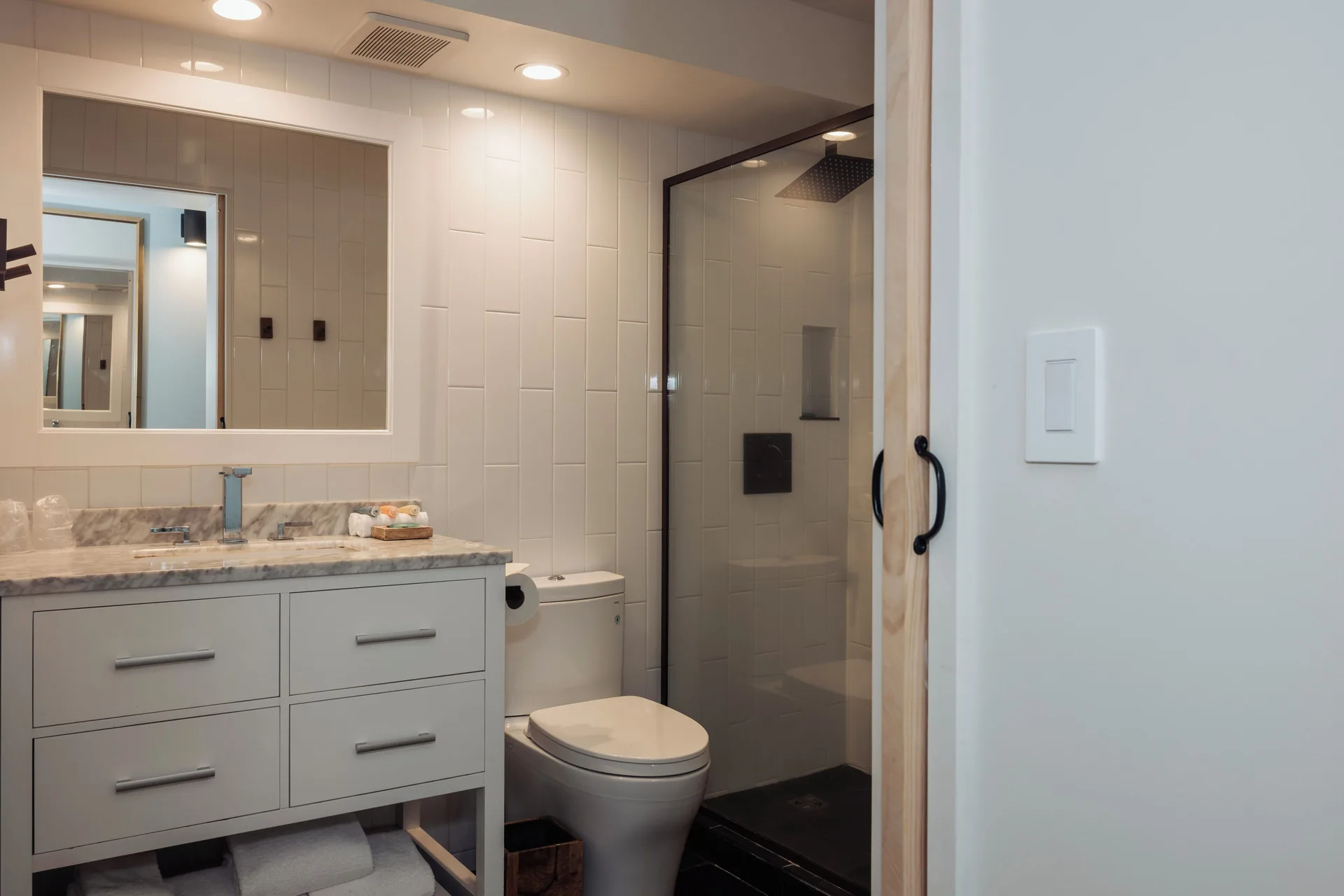 Ali'i Waikiki bathroom at Hotel La Croix with vanity, mirror, toilet, and glass-enclosed shower.