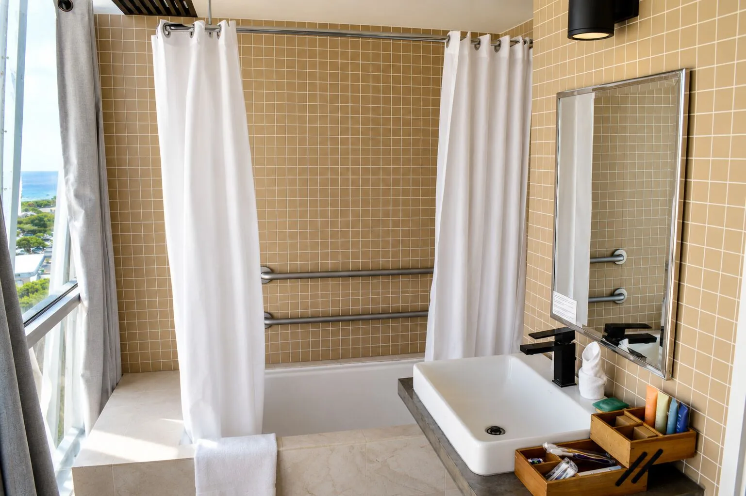 Penthouse Hoku Skyline Honolulu bathroom with tub, sink, and window at Hotel La Croix.