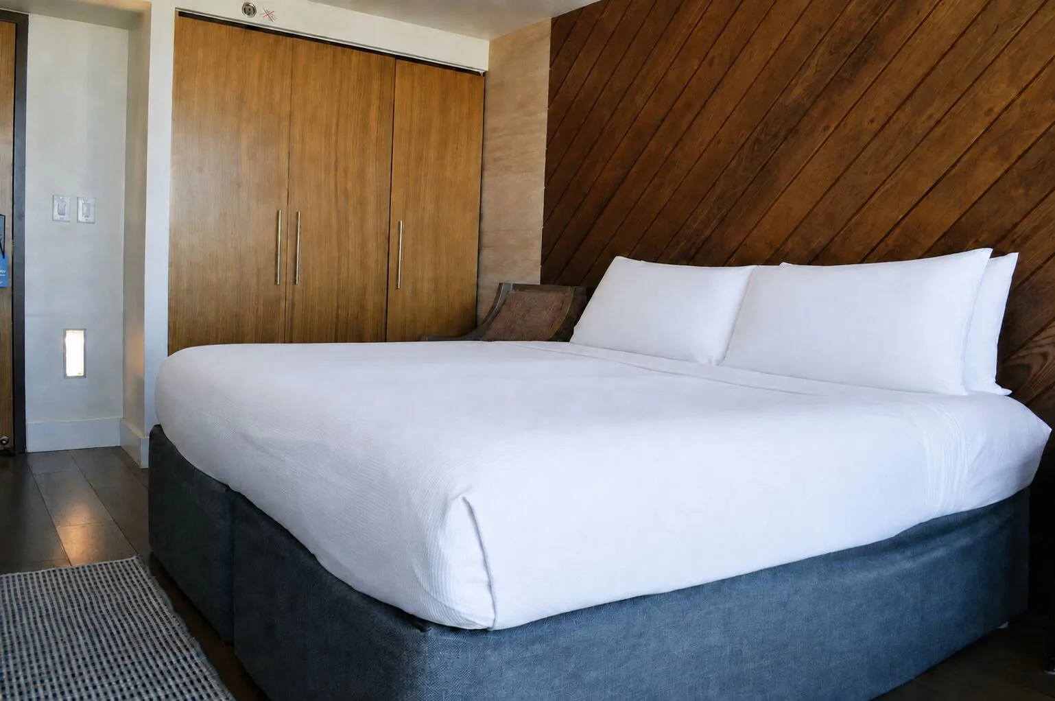 King bed, wood closet doors, and paneled wall in Penthouse Hoku at Hotel La Croix.