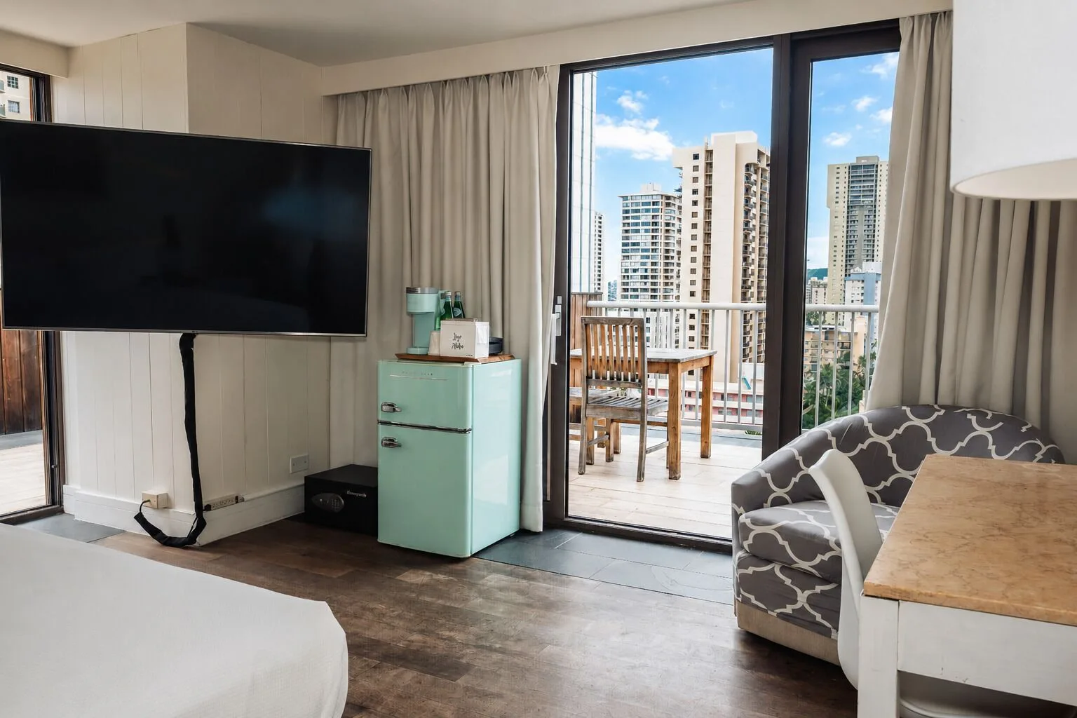 Penthouse Hoku Terrace ADA seating, TV, and balcony doors at Hotel La Croix.