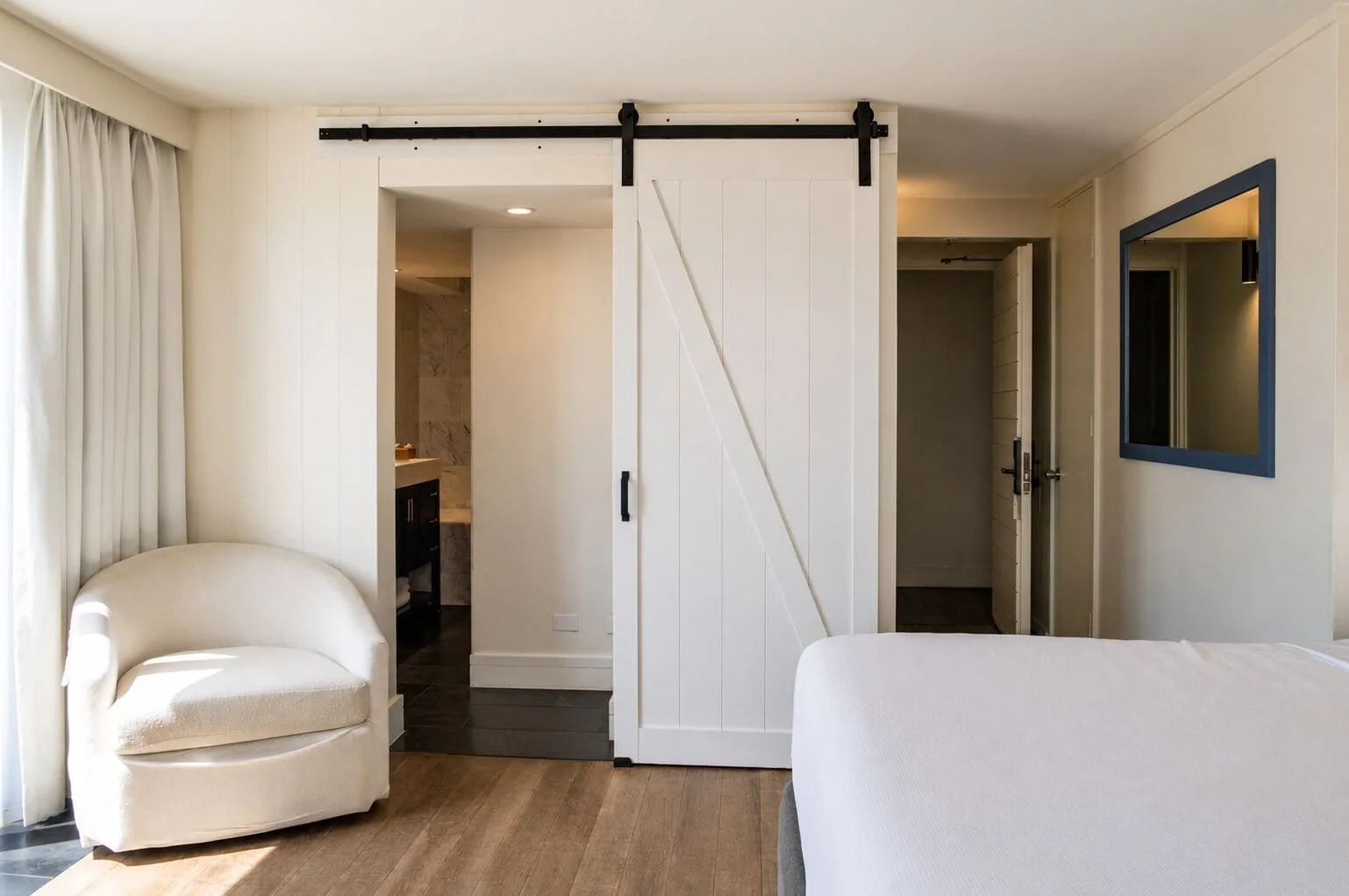 Guest room seating area with sliding bathroom door in Penthouse Hoku Terrace at Hotel La Croix.