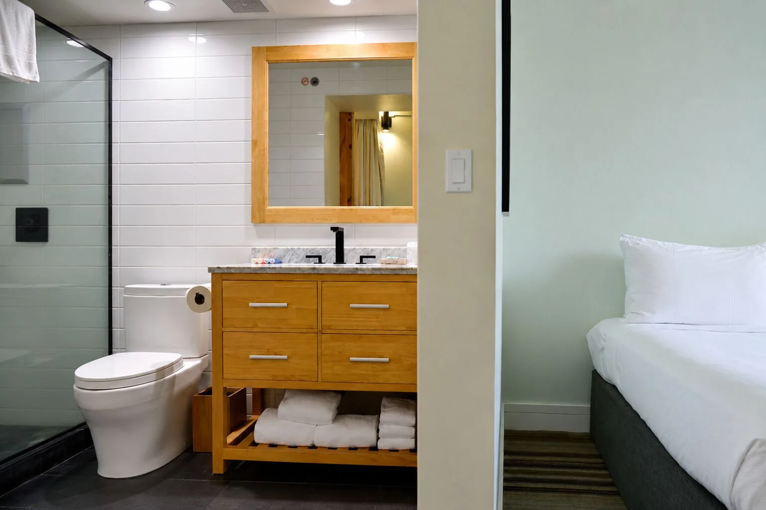 Bathroom vanity and part of a bed in a Premium Kalakaua Haus room at Hotel La Croix.