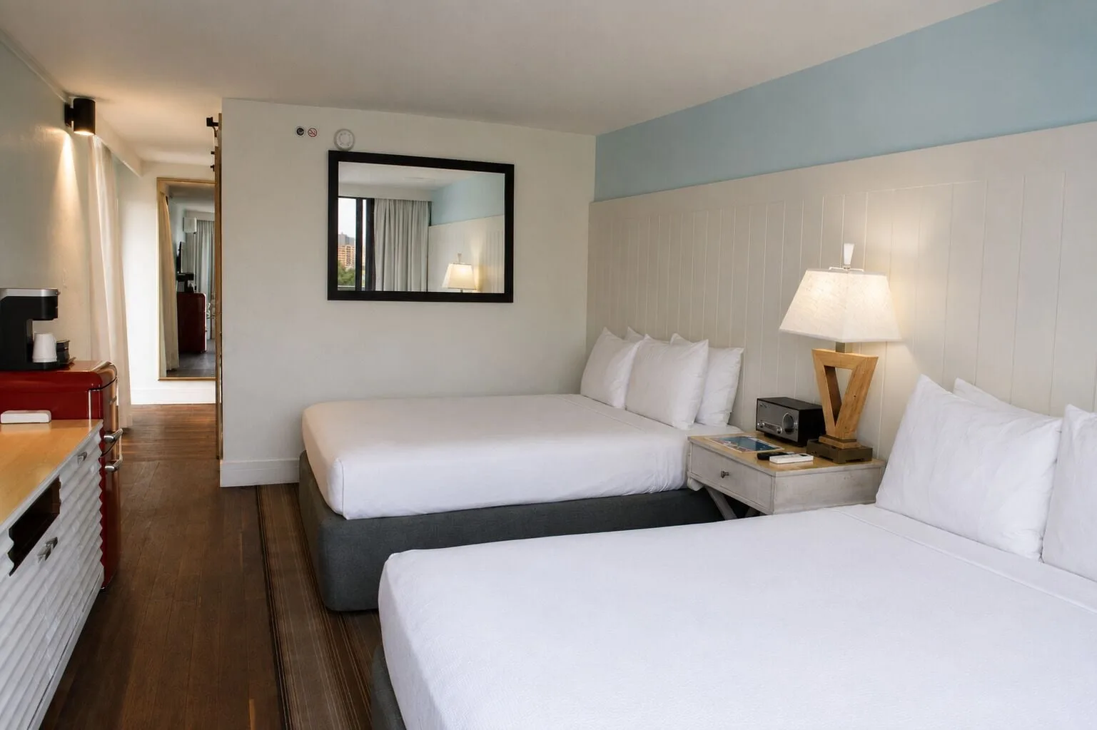 Two white beds in a Premium Kalakaua Haus Corner room at Hotel La Croix.