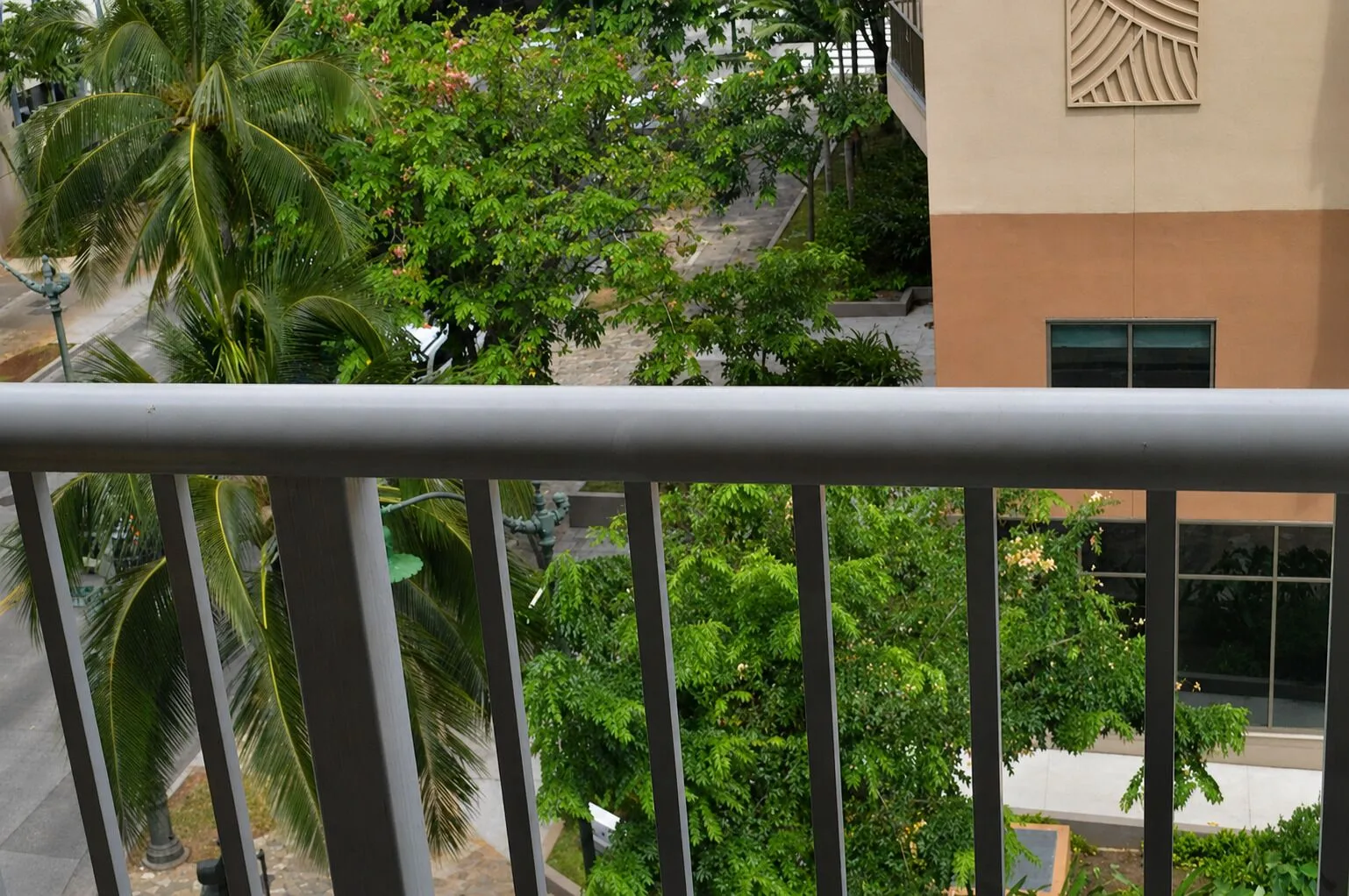 Balcony railing with palm trees and nearby building view at Hotel La Croix.