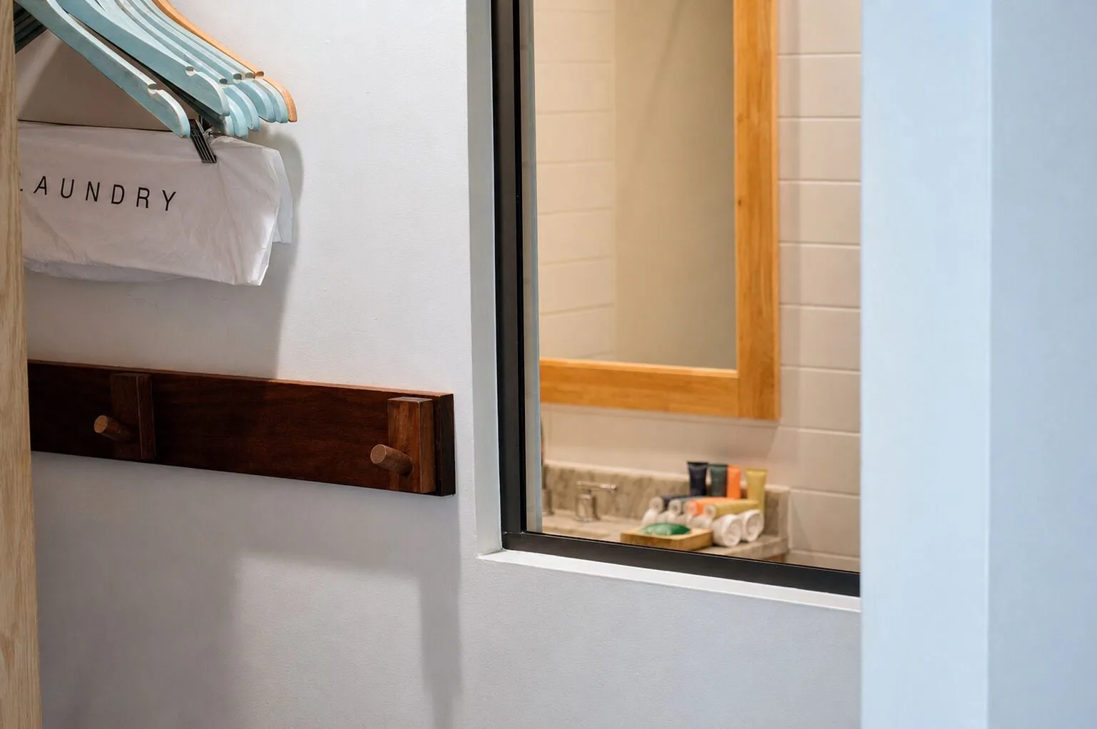 Closet hooks, hangers, and bathroom vanity view in a Premium Kalakaua Haus room at Hotel La Croix.