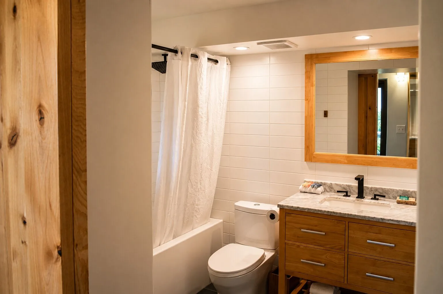 Bathroom with tub, shower curtain, and wood vanity in a Premium Kalakaua Haus room at Hotel La Croix.
