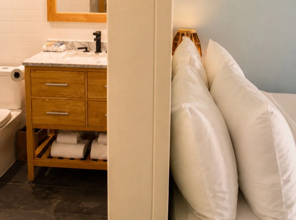 Premium Kalakaua Haus Oceanview room bath vanity and bed pillows at Hotel La Croix.