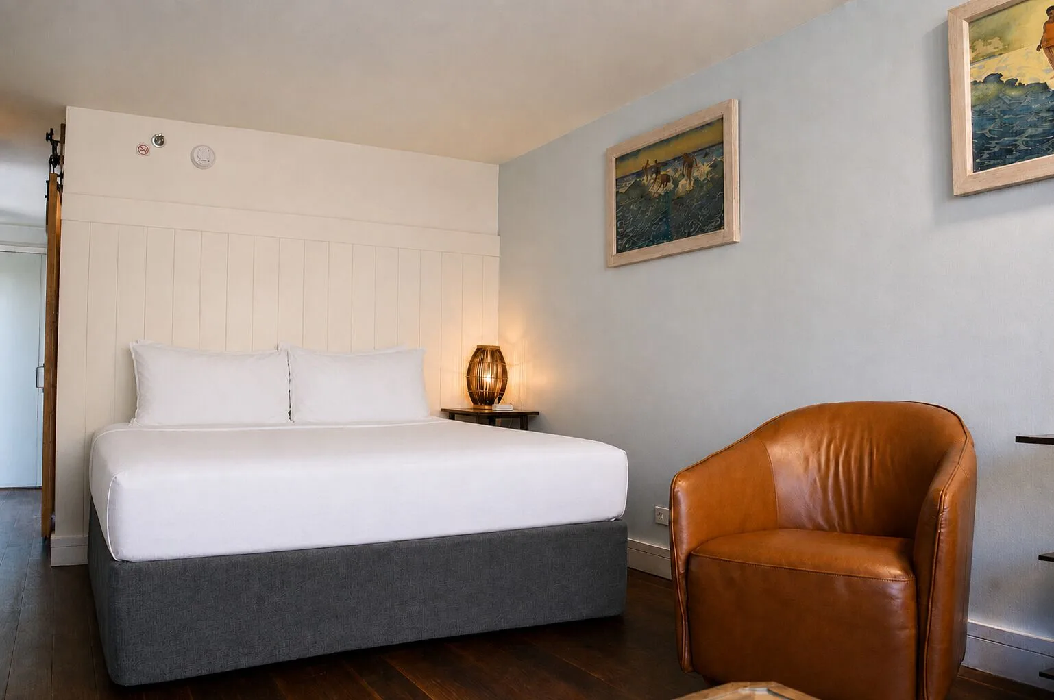 King bed and leather lounge chair in a Premium Kalakaua Haus room at Hotel La Croix.