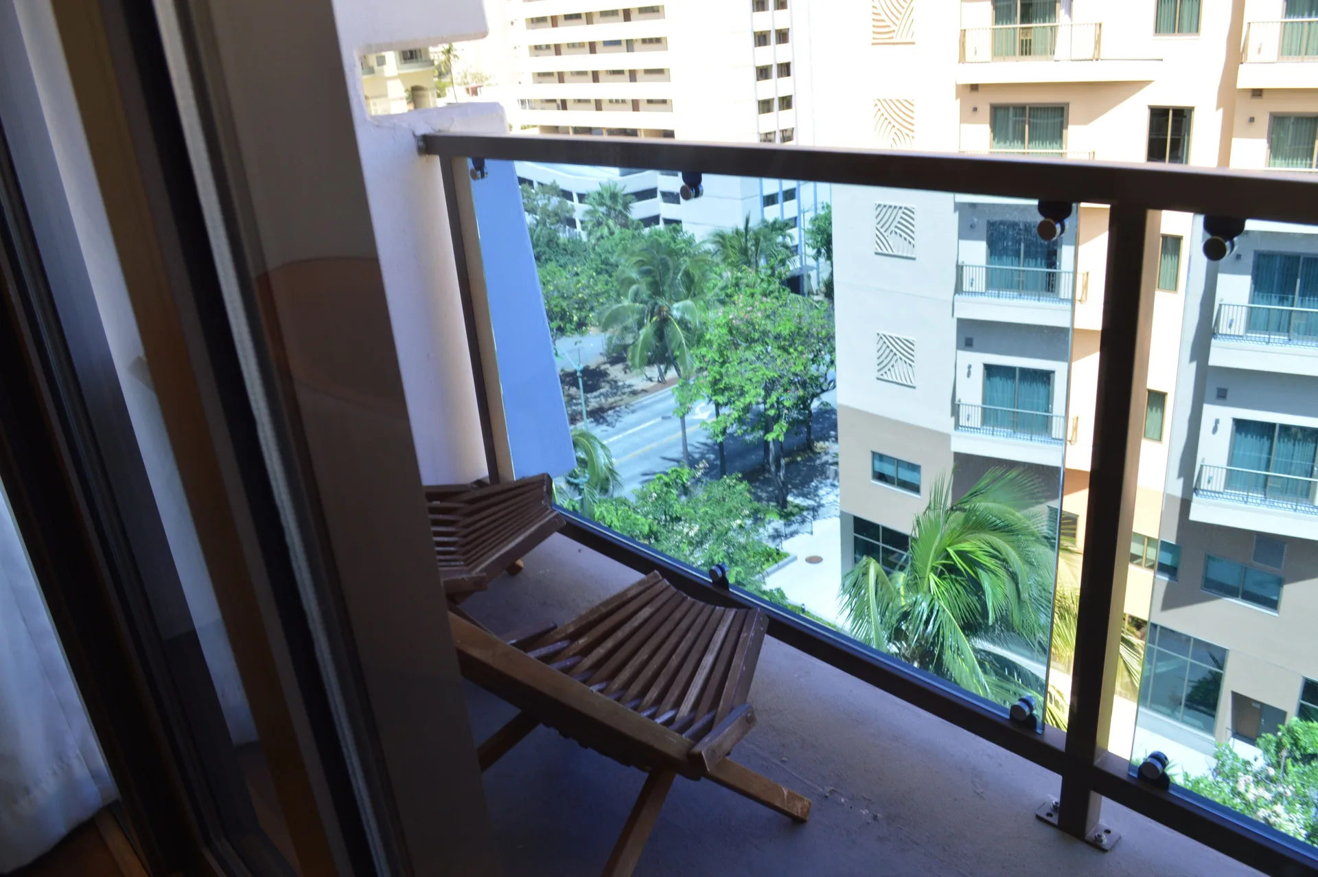 Second lanai with wooden chair and city view in a Premium Kalakaua Haus room at Hotel La Croix.