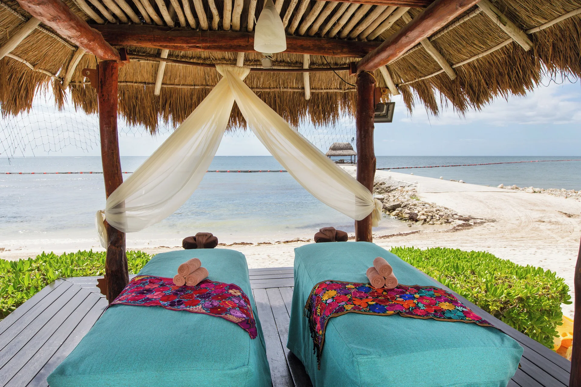Beachfront massage palapa with two treatment beds at Hotel Marina El Cid Spa & Beach Resort.