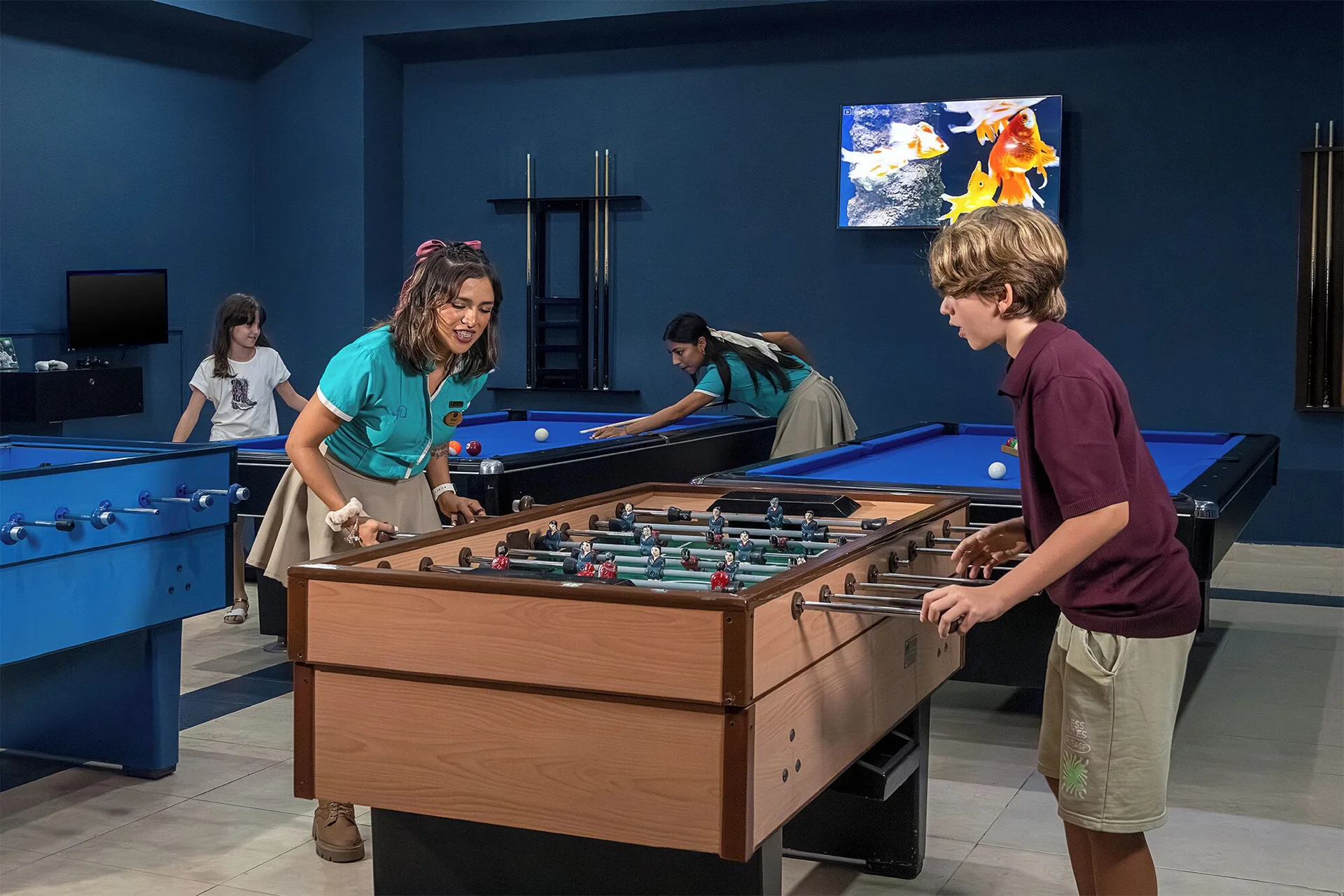 Children play foosball and billiards in the game room at Hotel Marina El Cid Spa & Beach Resort.