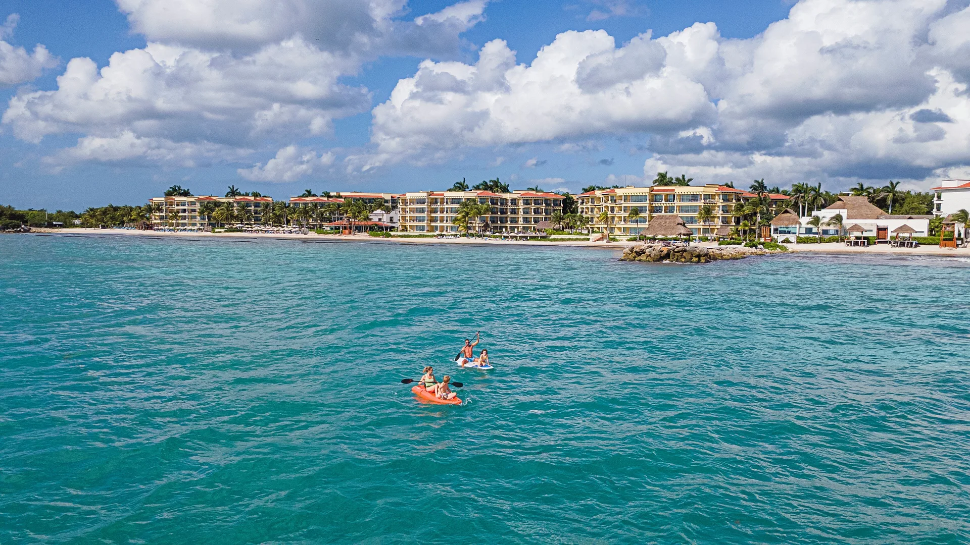 Kayakers on turquoise water off Hotel Marina El Cid Spa & Beach Resort.