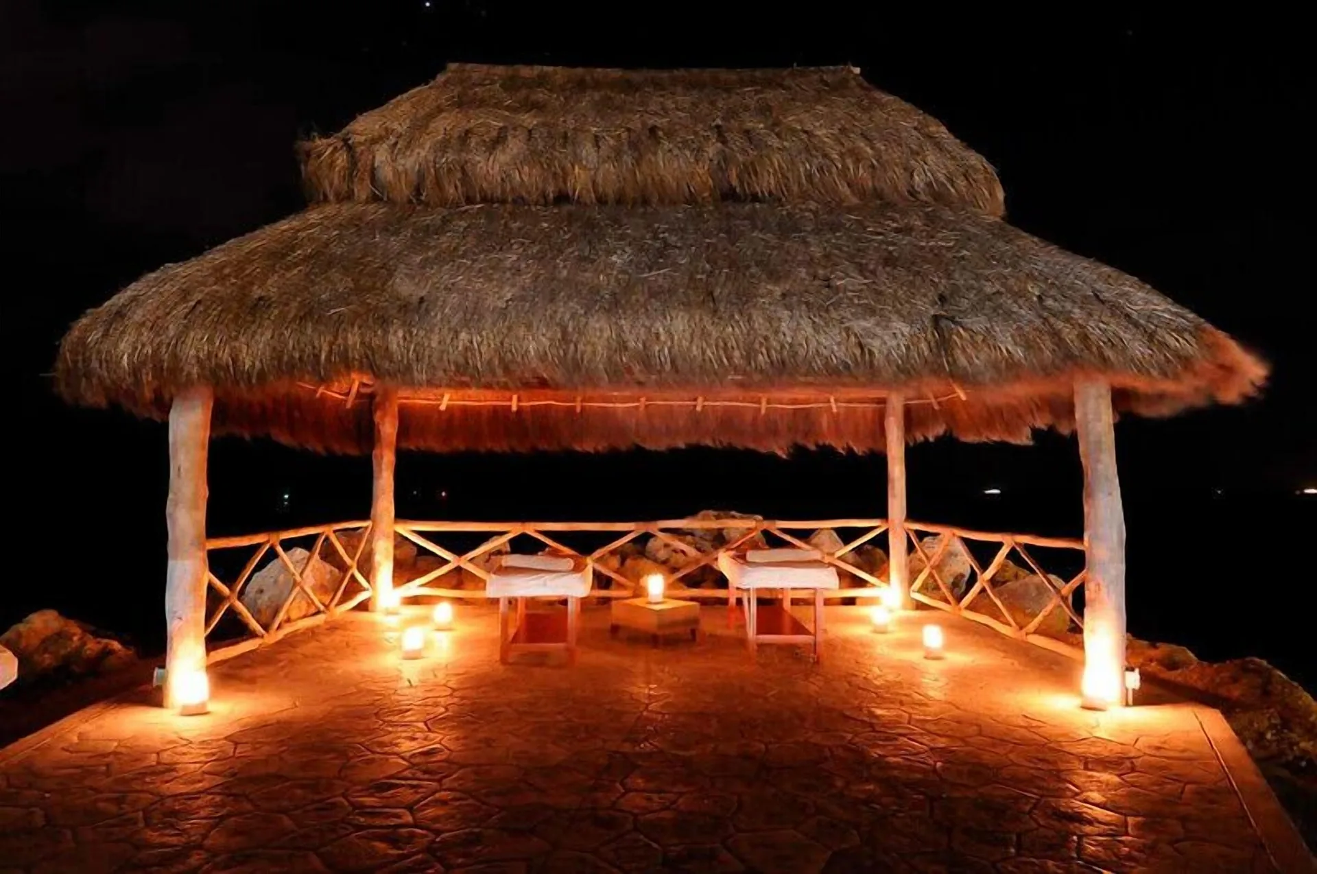 Thatched seaside massage palapa lit at night at Hotel Marina El Cid Spa & Beach Resort.