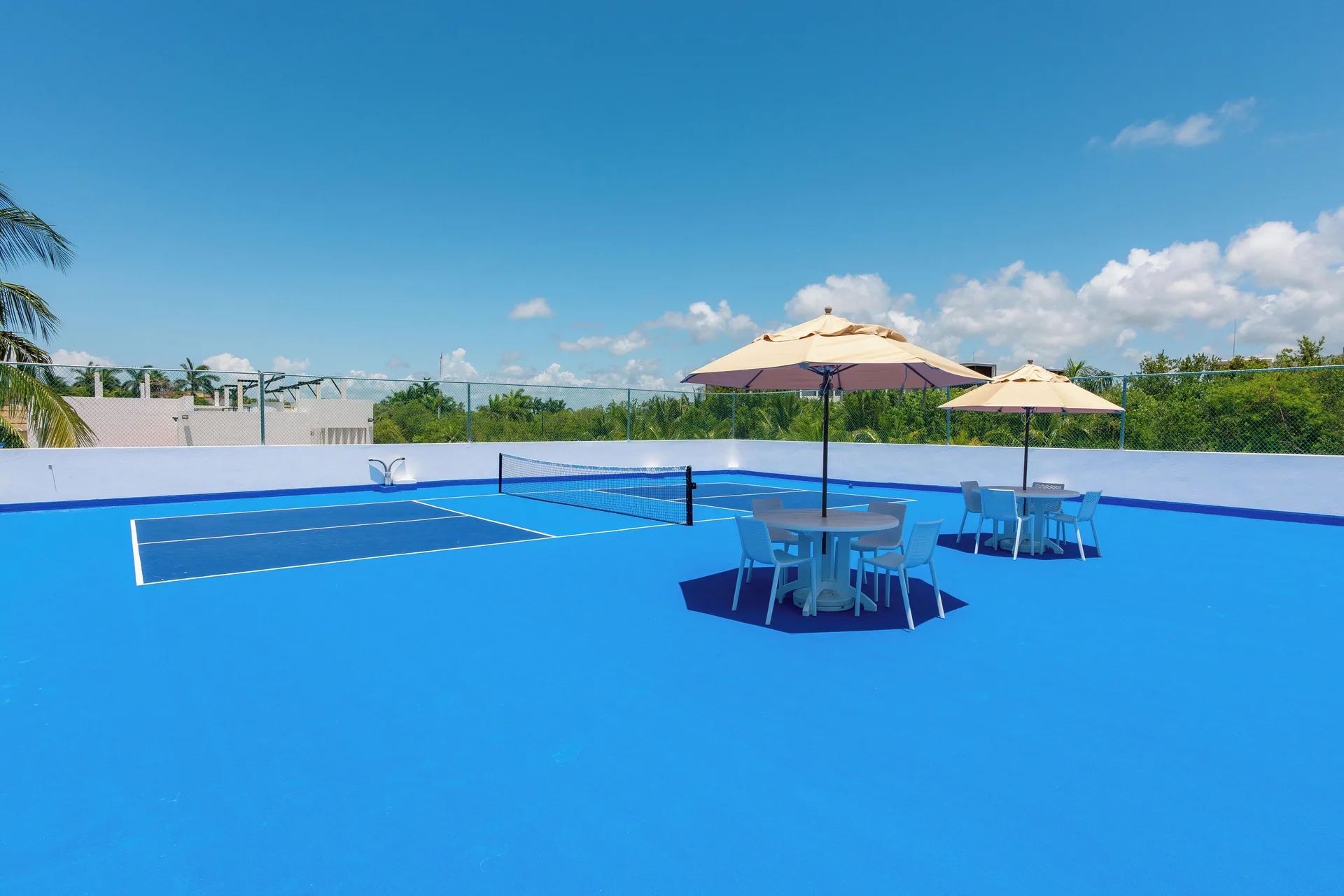 Blue rooftop pickleball courts with shaded tables at Hotel Marina El Cid Spa & Beach Resort.