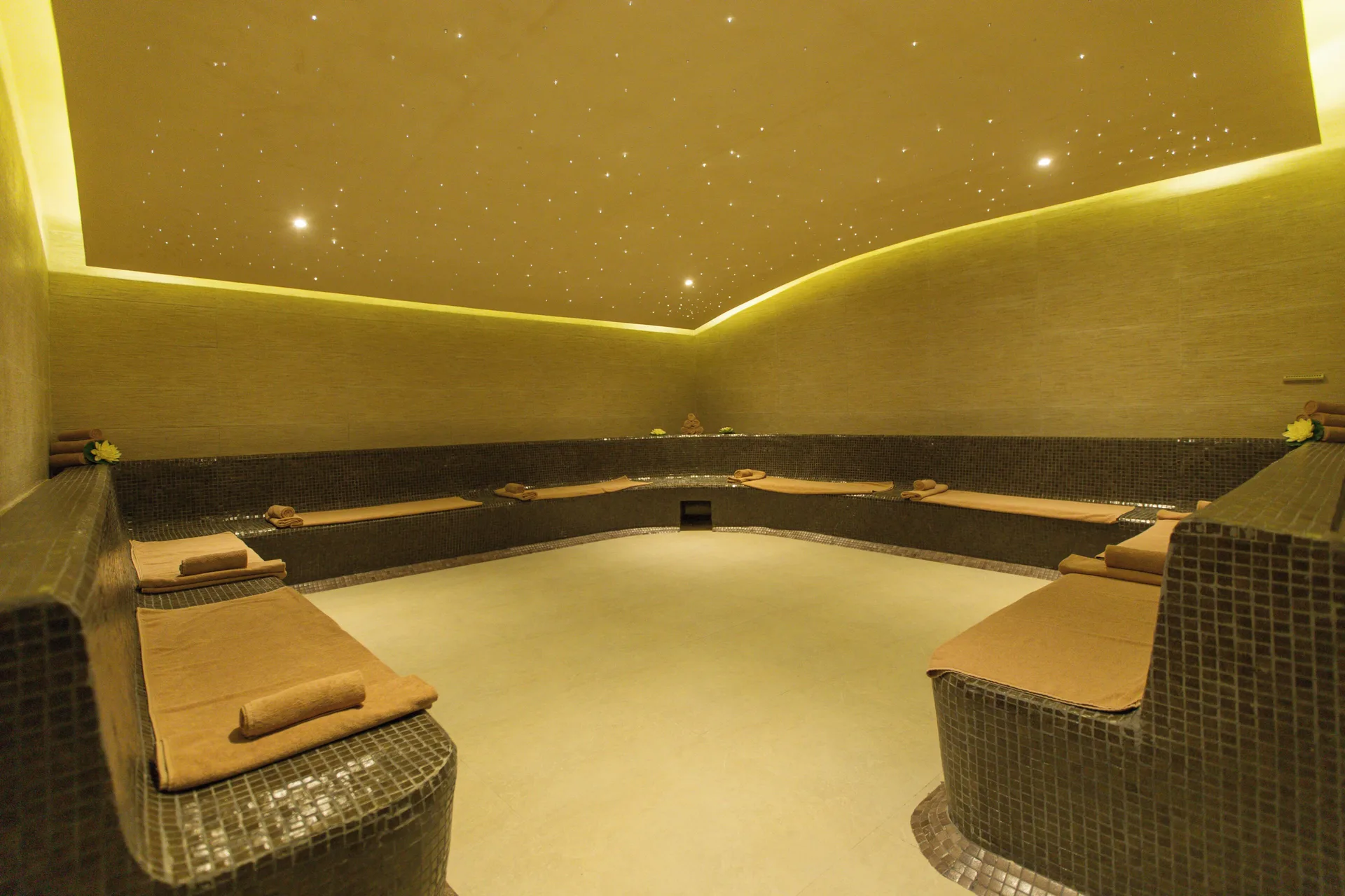 Dim spa relaxation room with tiled loungers at Hotel Marina El Cid Spa & Beach Resort.