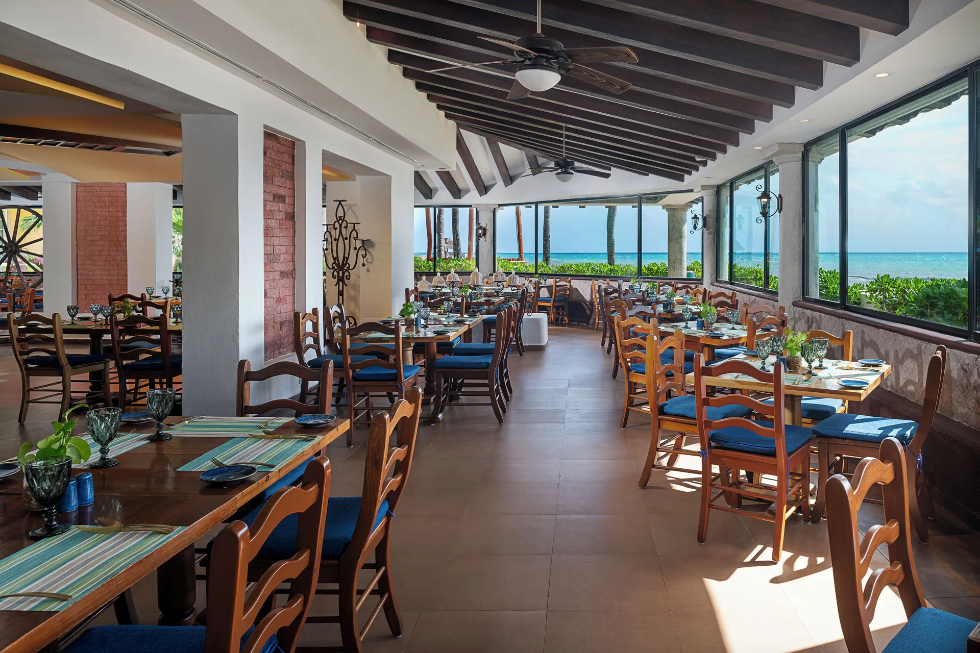 Oceanfront restaurant seating with wooden chairs at Hotel Marina El Cid Spa & Beach Resort.