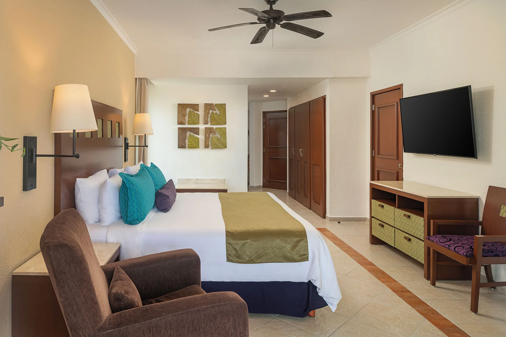 Luxury Room with king bed, armchair, and TV at Hotel Marina El Cid Spa & Beach Resort.
