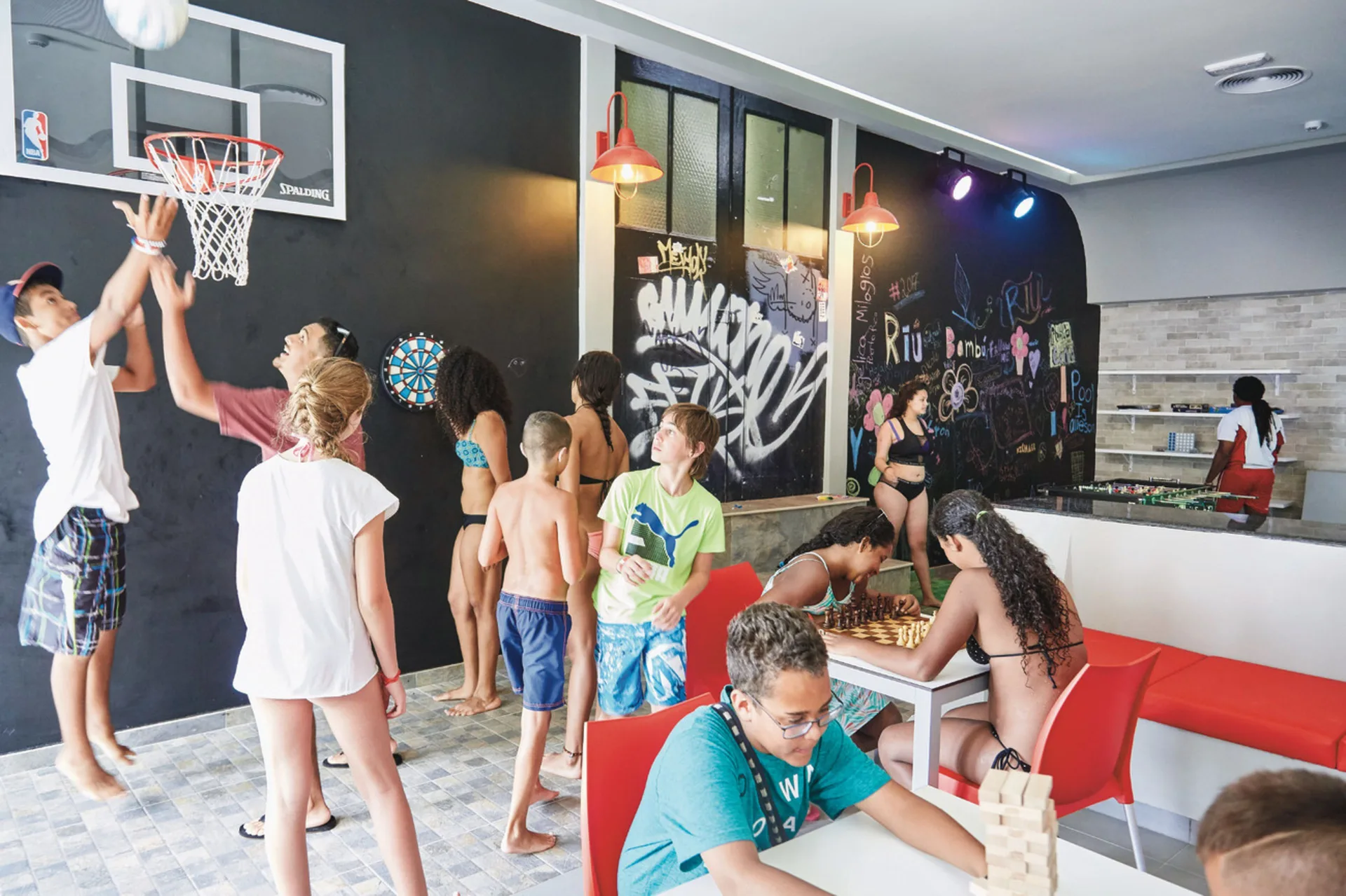 Teens playing basketball, chess, and table games at Hotel Riu Bambu.