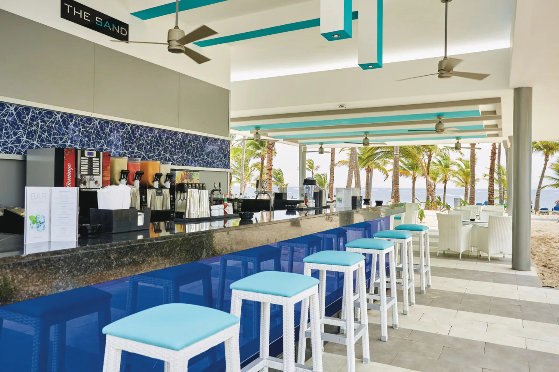 Beachfront bar counter with stools and ocean palms at Hotel Riu Bambu.
