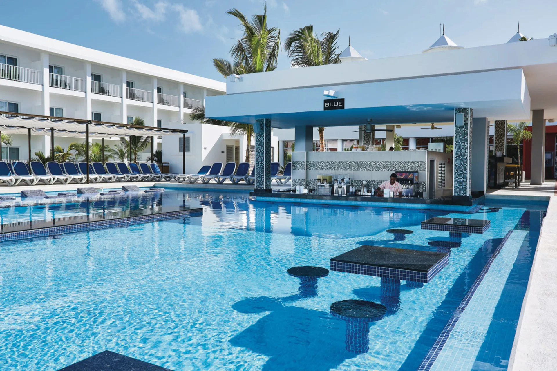 Blue swim-up bar beside the pool with in-water tables at Hotel Riu Bambu.