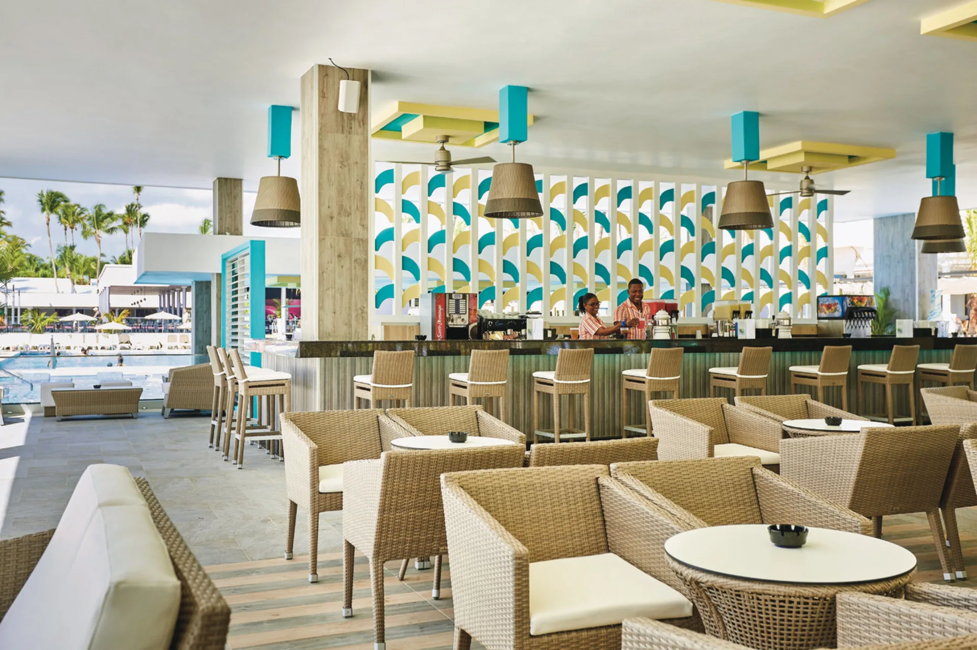 Open-air lounge bar with wicker seating by the pool at Hotel Riu Bambu.