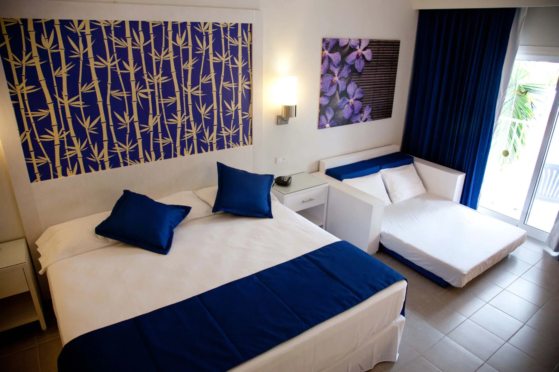 Family Room bed and sofa bed beside balcony doors at Hotel Riu Bambu.