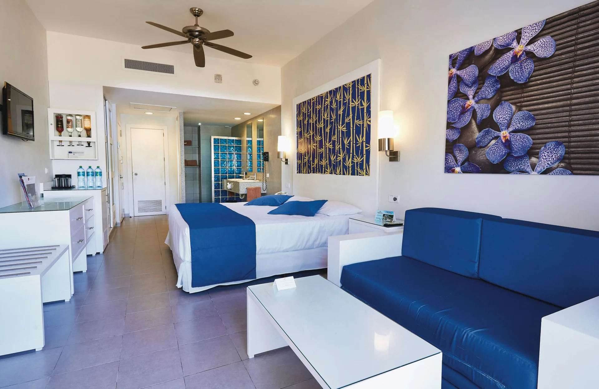 Family Room with bed, sofa, TV and refreshment area at Hotel Riu Bambu.