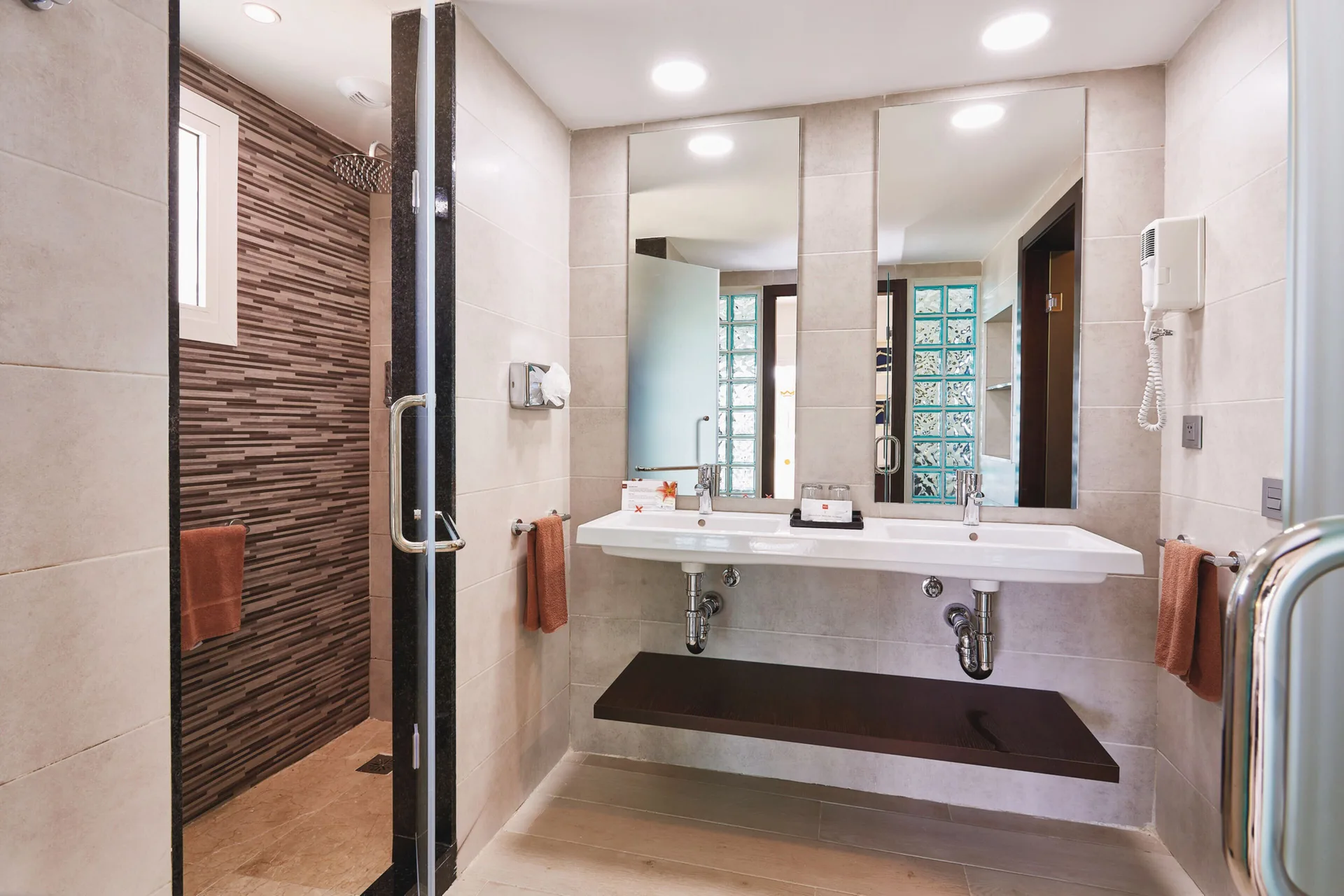 Junior Suite bathroom with double sink vanity and walk-in shower at Hotel Riu Bambu.