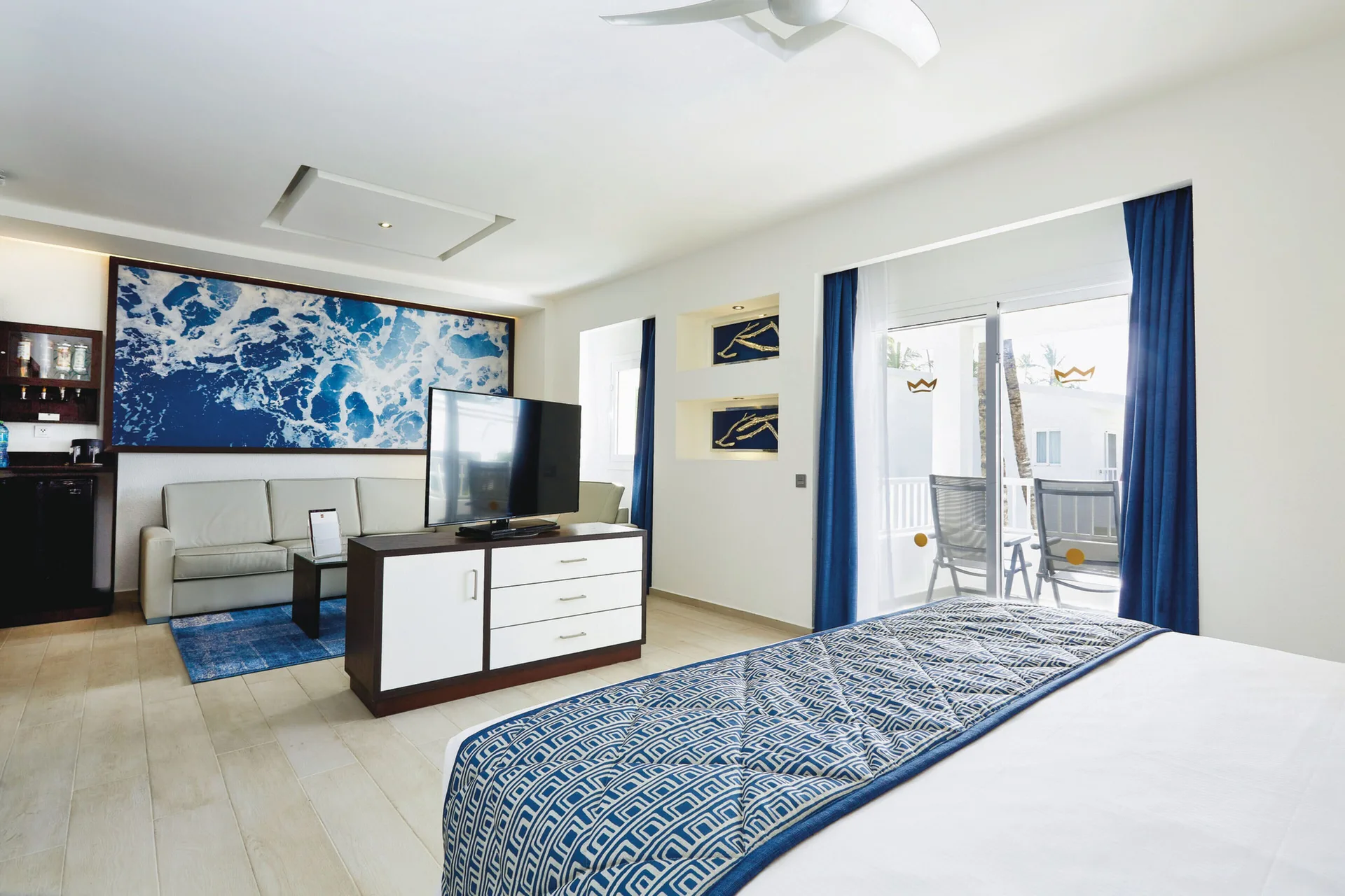Junior Suite with bed, sofa, TV and balcony doors at Hotel Riu Bambu.