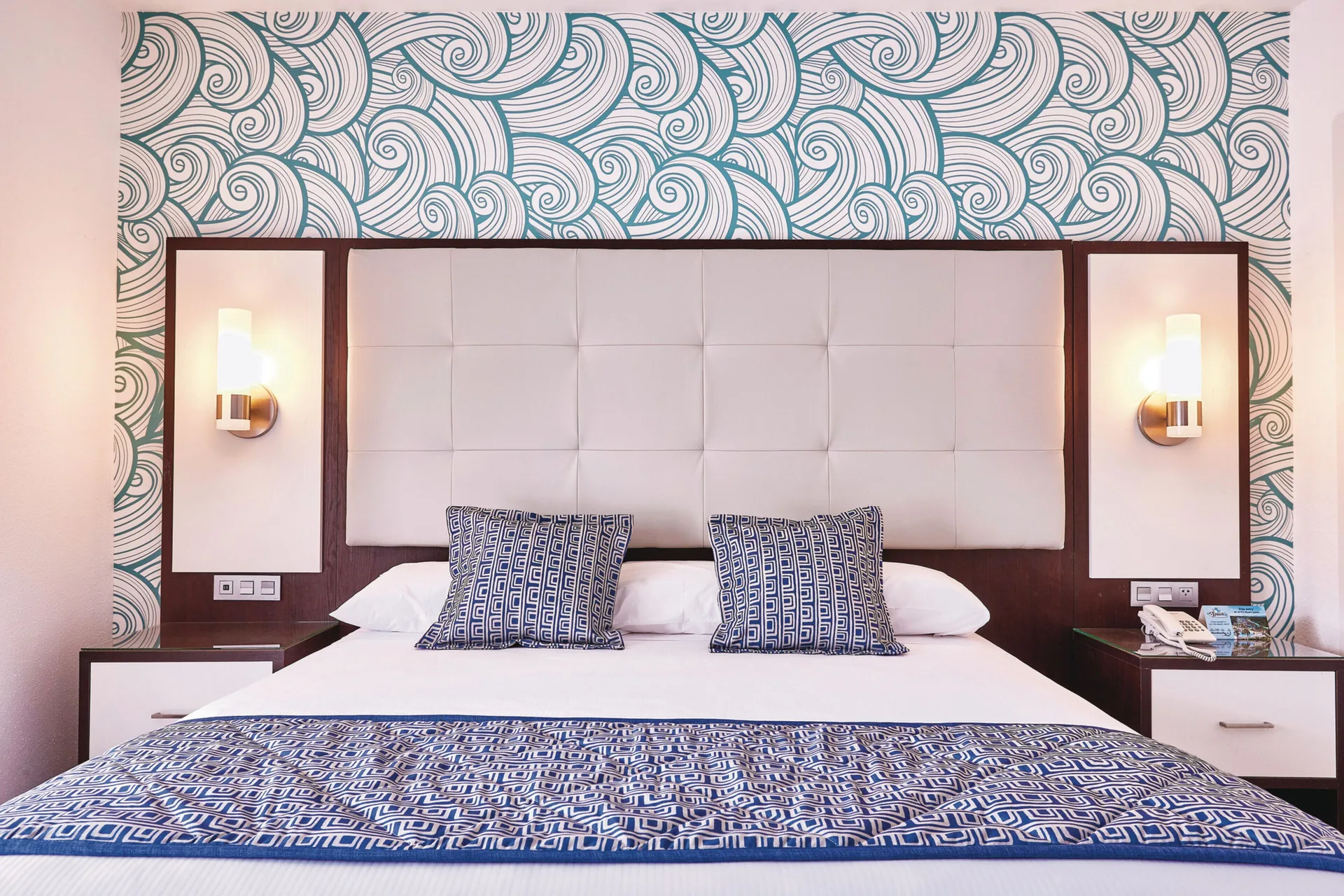 Junior Suite king bed with padded headboard and patterned wall at Hotel Riu Bambu.