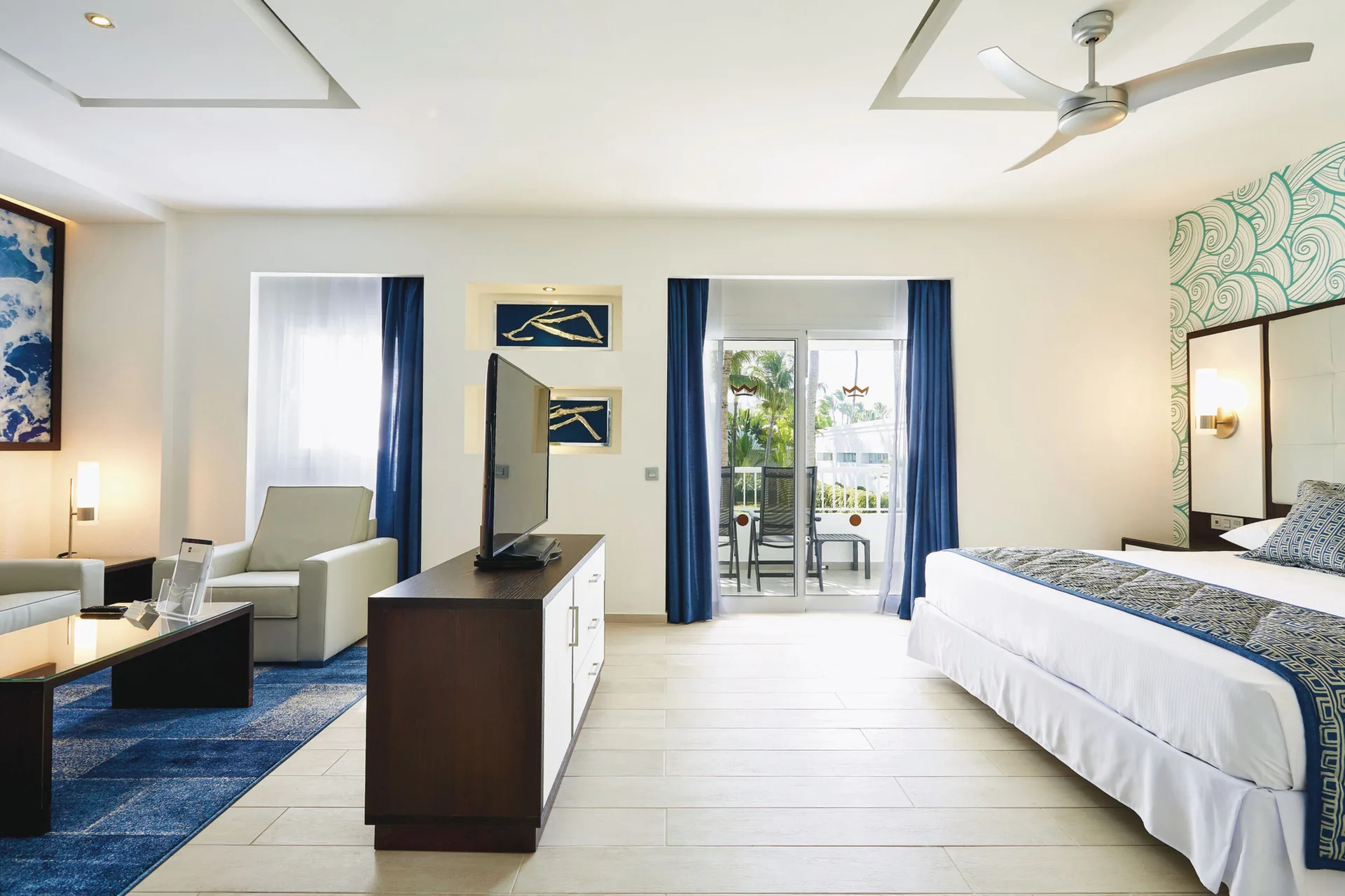 Junior Suite with king bed, TV console, seating area and balcony at Hotel Riu Bambu.