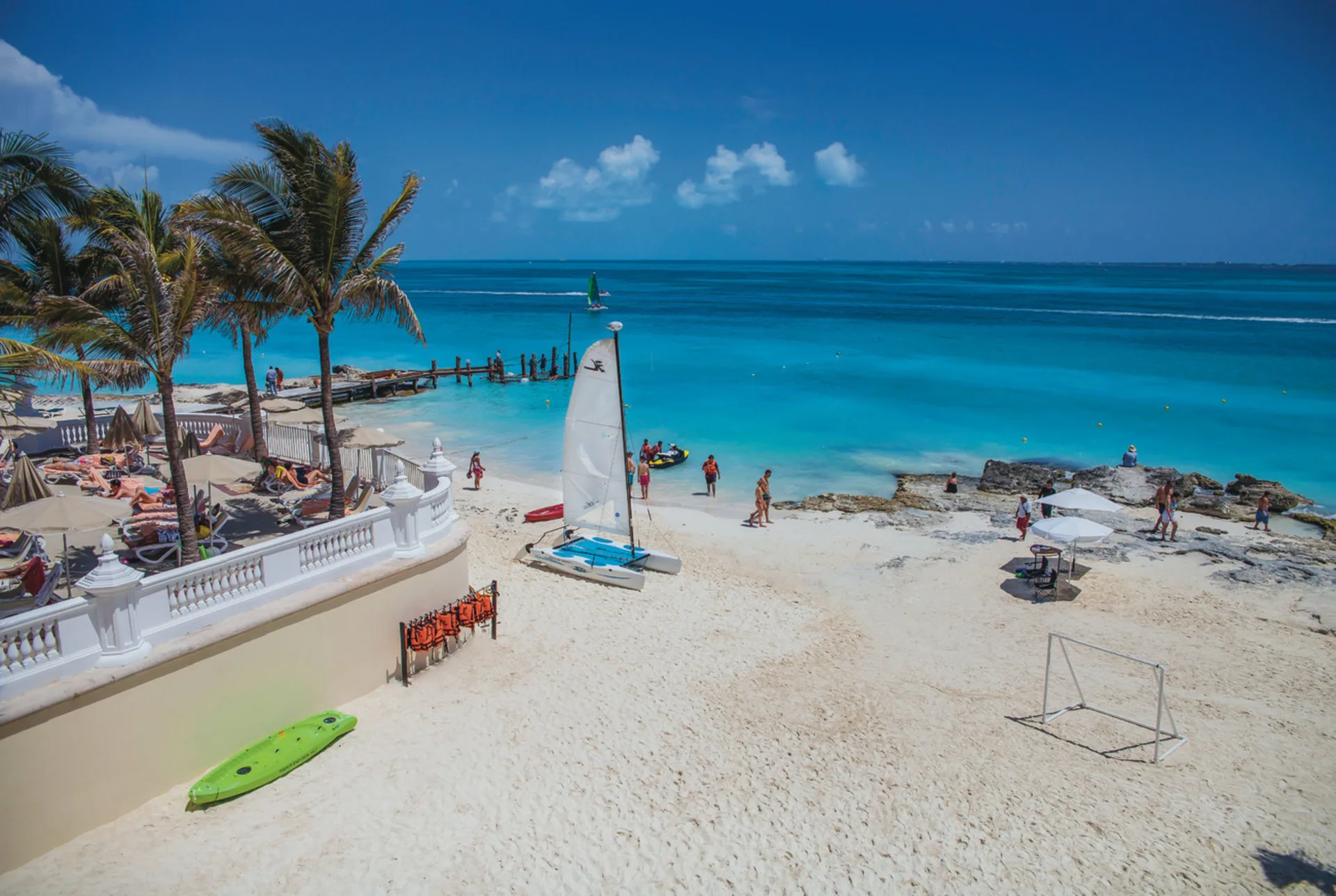 Beachfront with sailboat, loungers, palms, and turquoise sea at Hotel Riu Cancun.