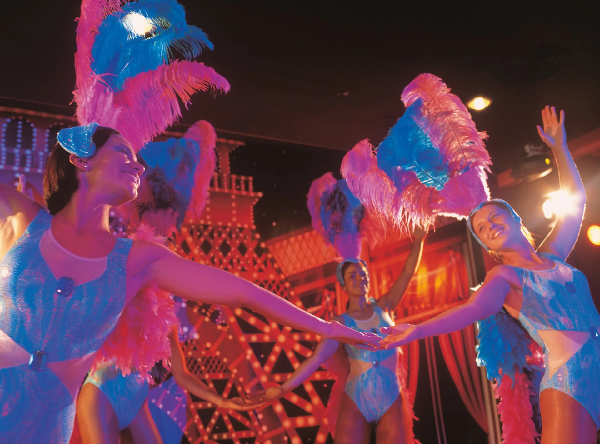 Feather-costumed dancers performing on stage at Hotel Riu Cancun.
