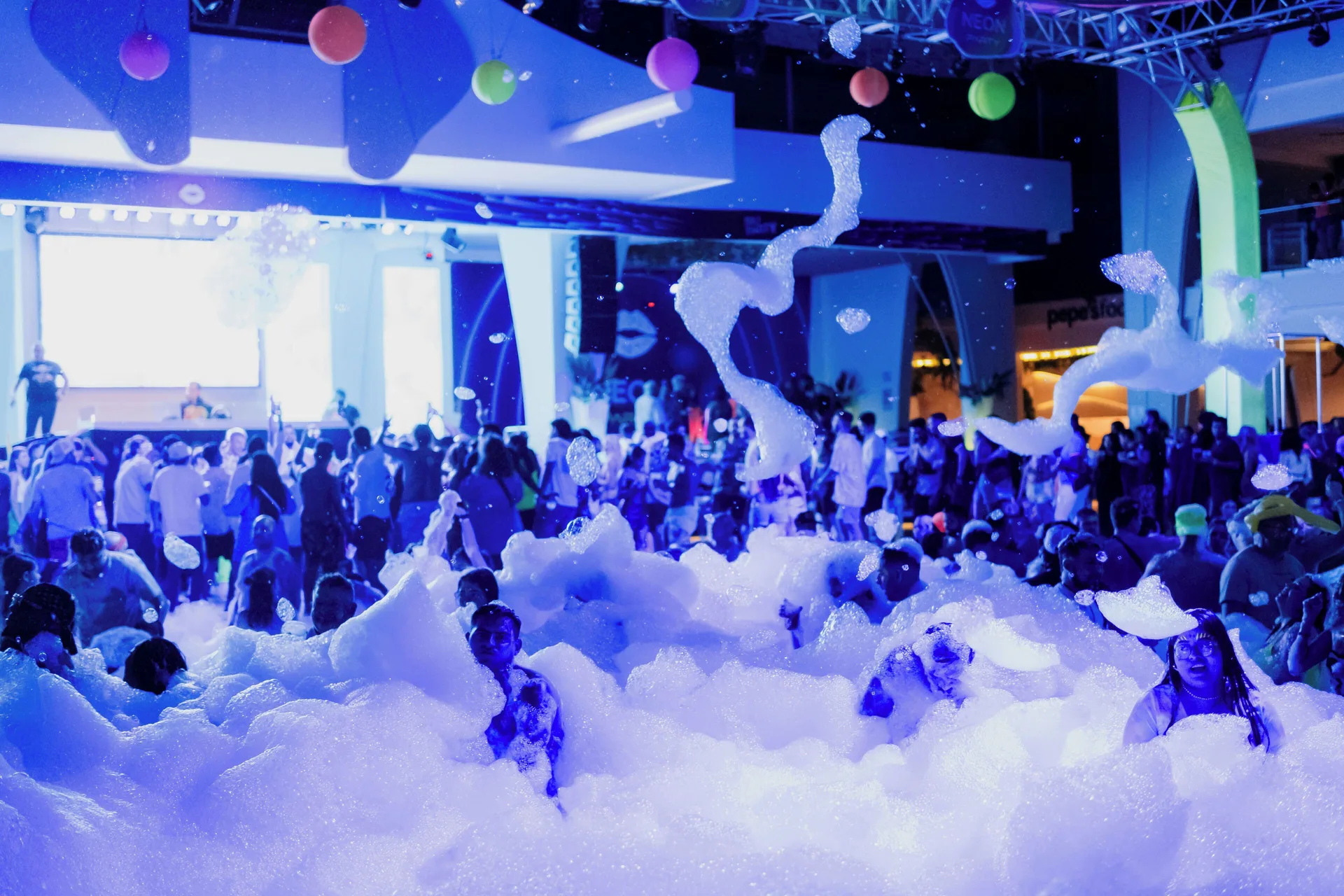 Foam party crowd under blue lighting at Hotel Riu Cancun.