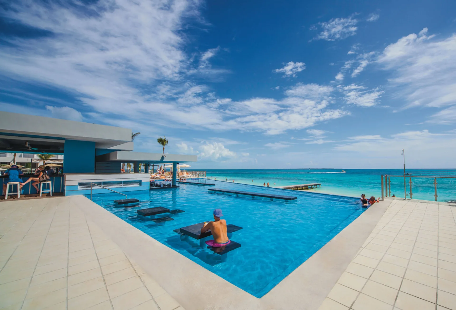Infinity pool with swim-up bar and Caribbean Sea at Hotel Riu Cancun.