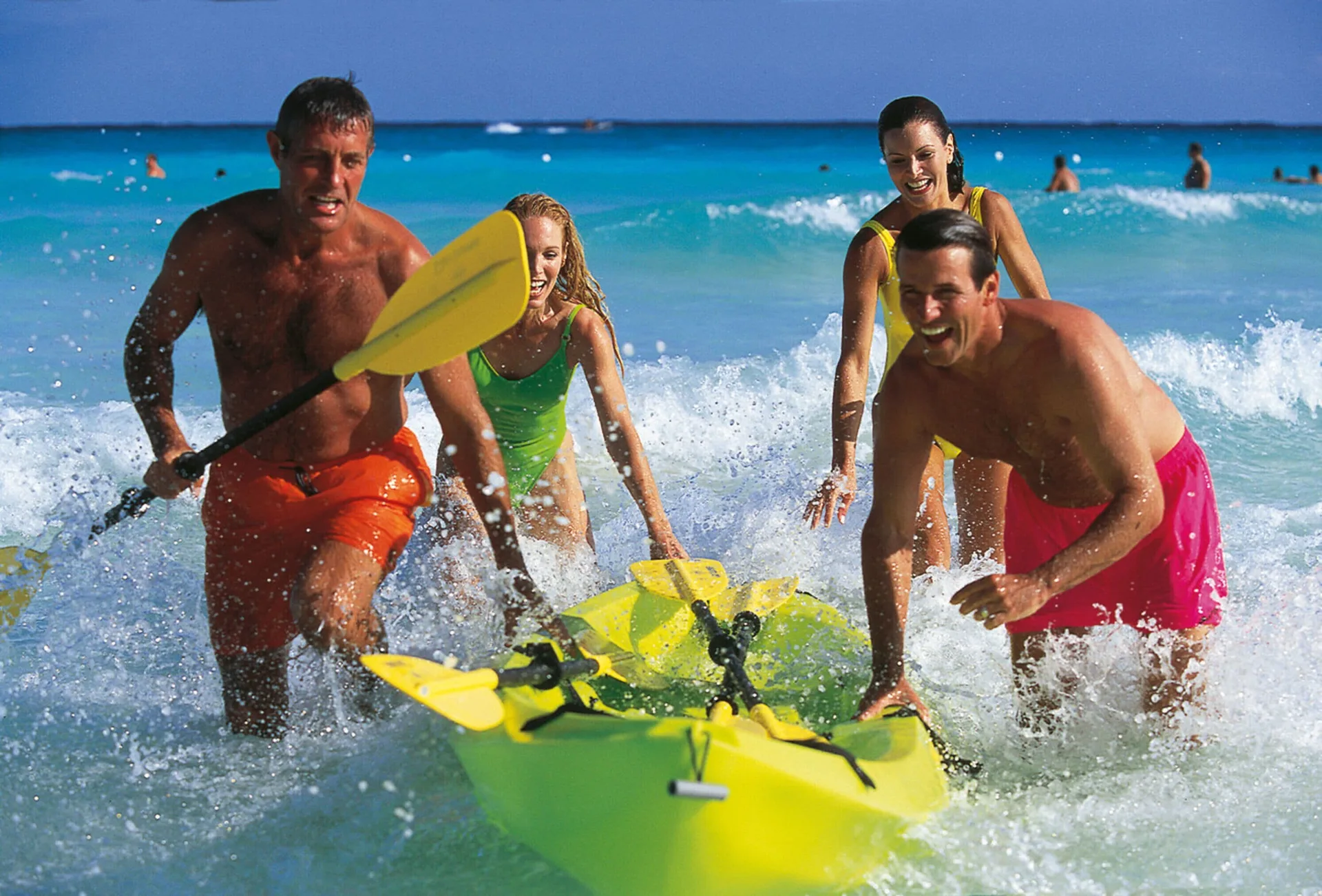 Guests splash through the surf with yellow kayaks at Hotel Riu Cancun.