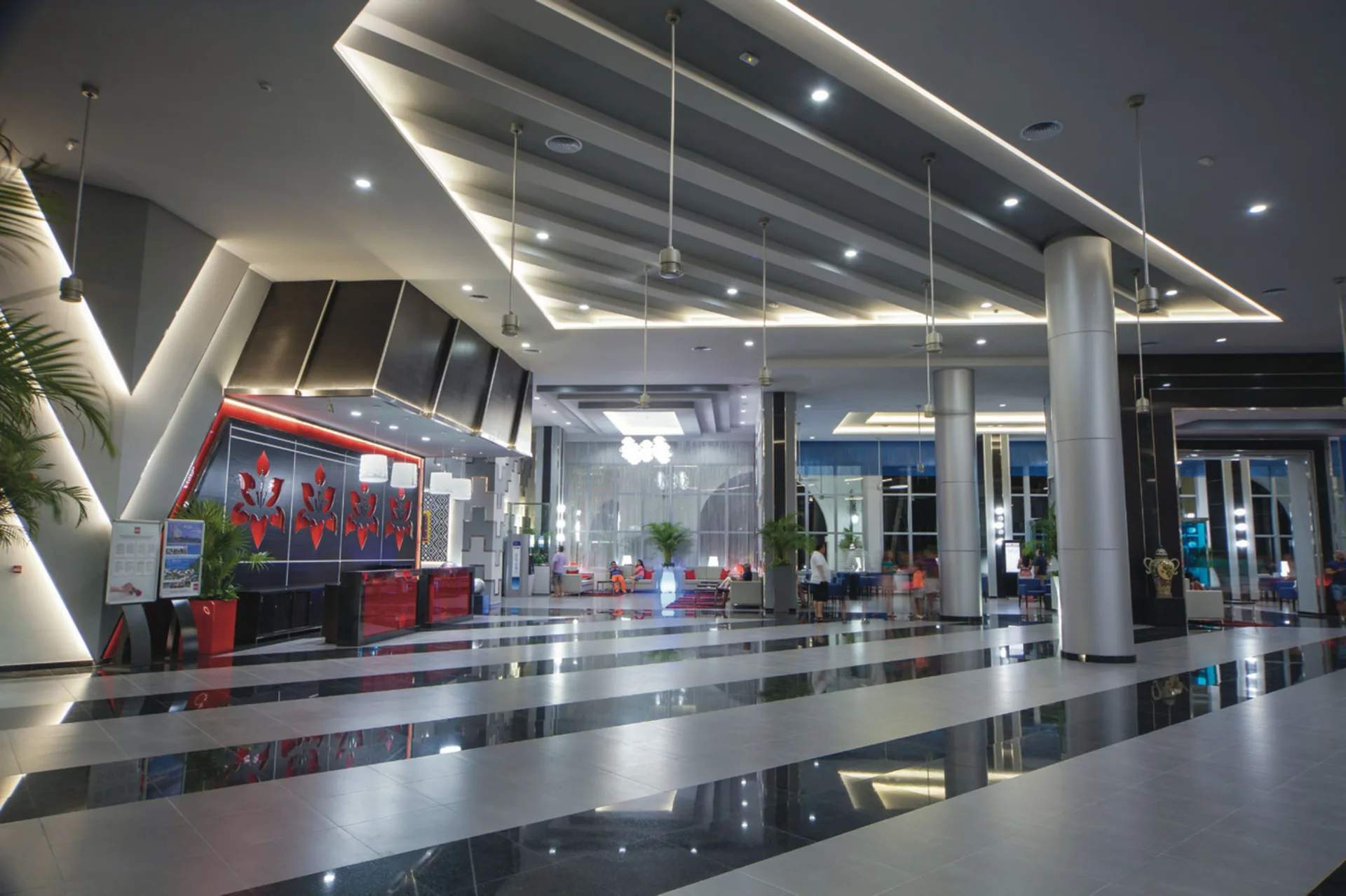 Modern lobby at Hotel Riu Cancun with glossy floors, columns, and red reception area.