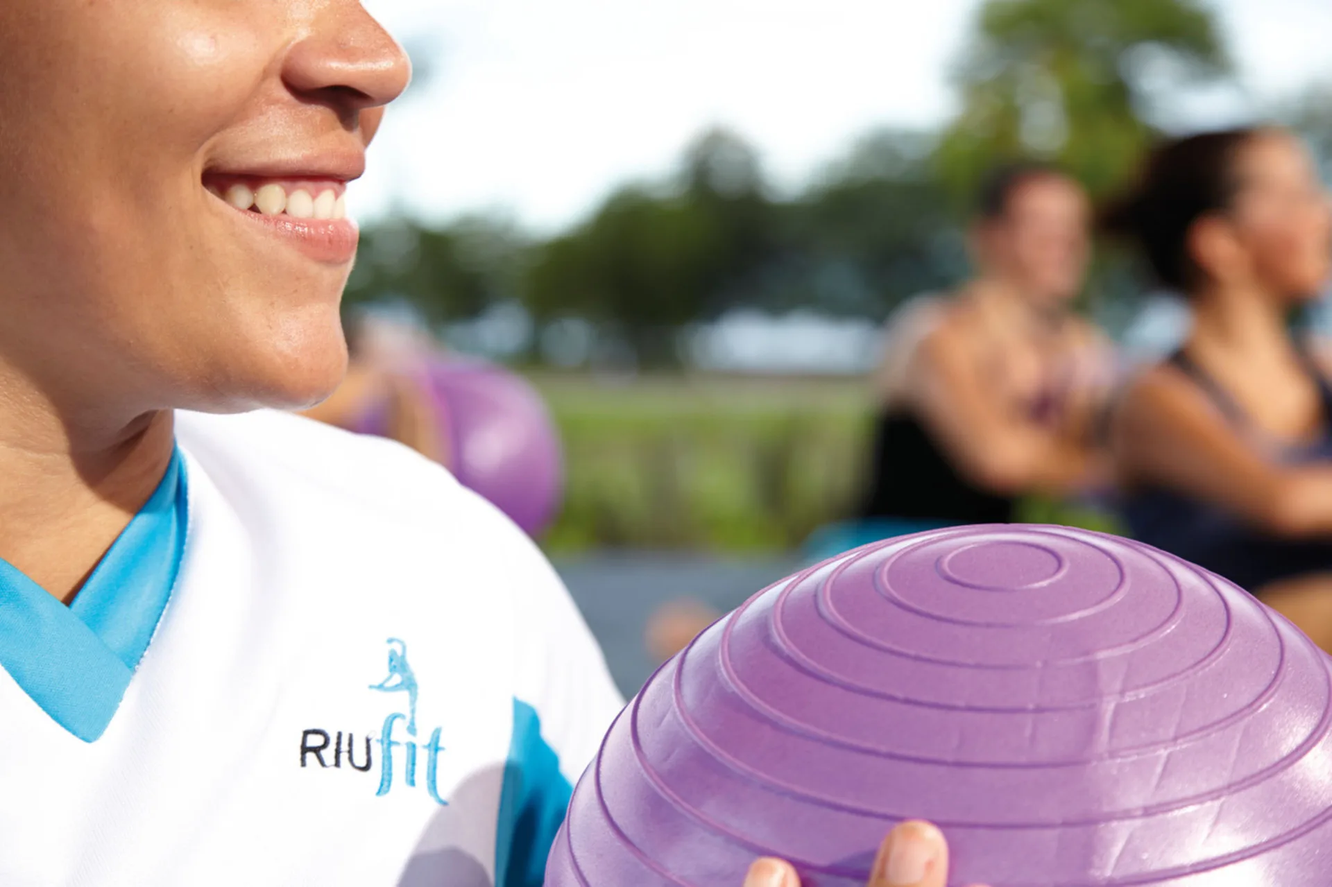 Fitness instructor holding a purple exercise ball at Hotel Riu Cancun.