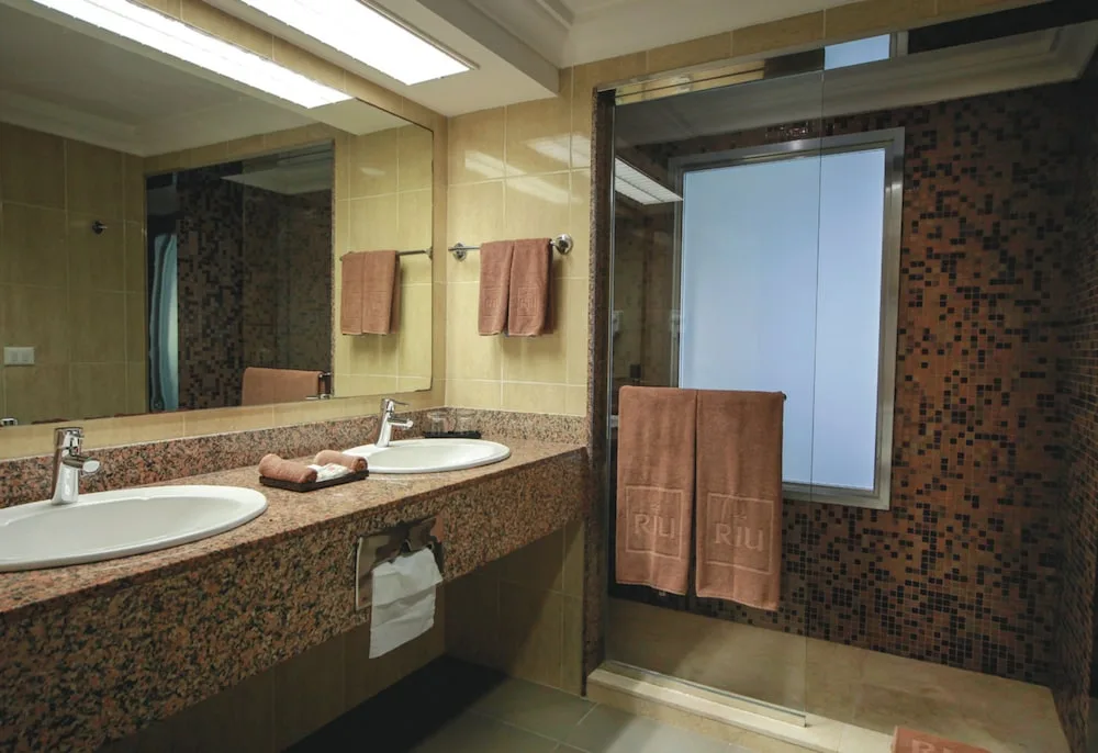 Junior Suite Ocean View bathroom vanity and mosaic-tile shower at Hotel Riu Cancun.