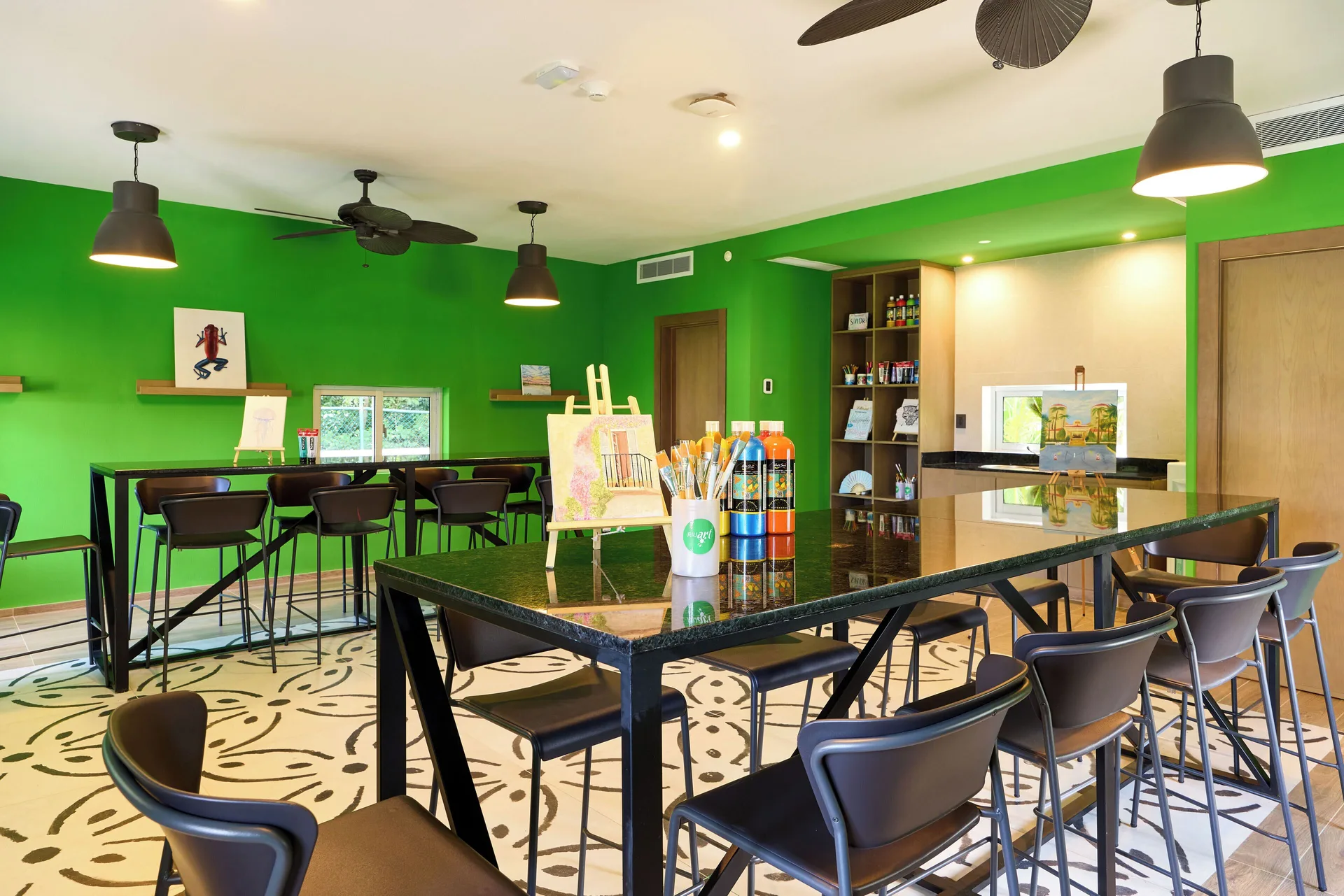 Art studio tables with paints and easels in a green room at Hotel Riu Guanacaste.