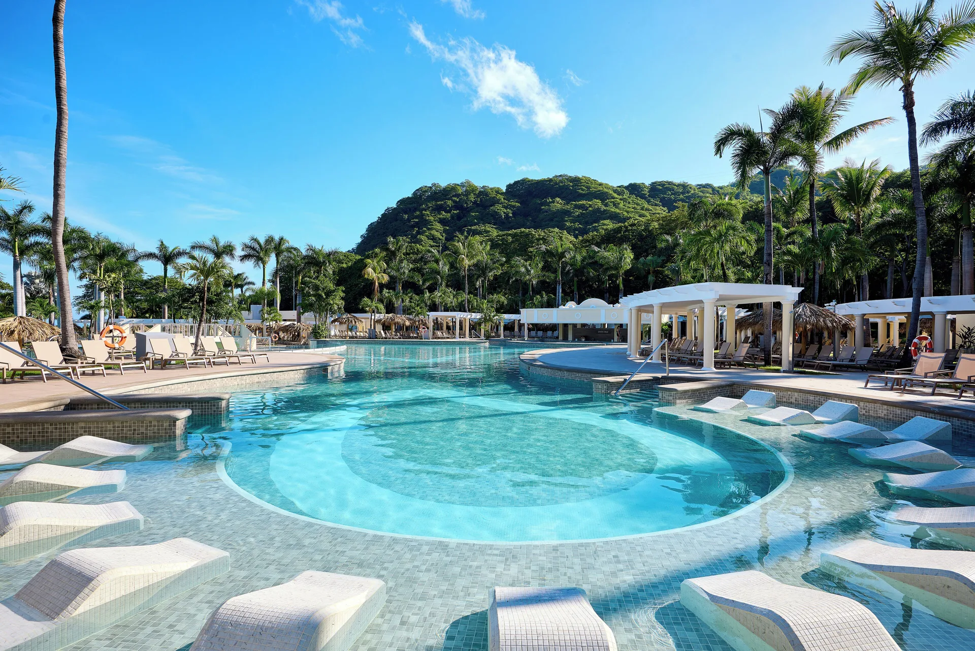 Lagoon-style pool with in-water loungers and palms at Hotel Riu Guanacaste.