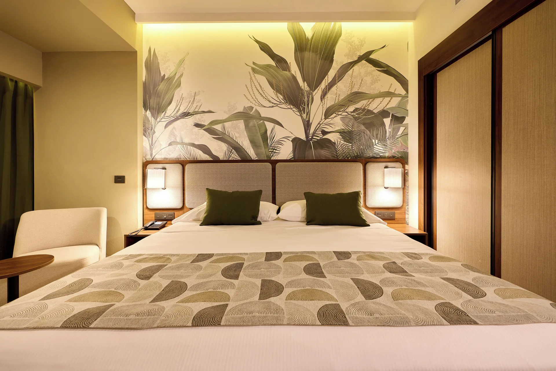 Family Suite bedroom with a king bed and leaf mural at Hotel Riu Guanacaste.
