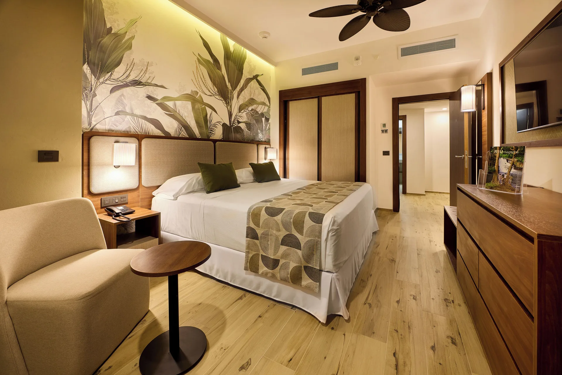 Family Suite king bedroom with chair, dresser and TV at Hotel Riu Guanacaste.