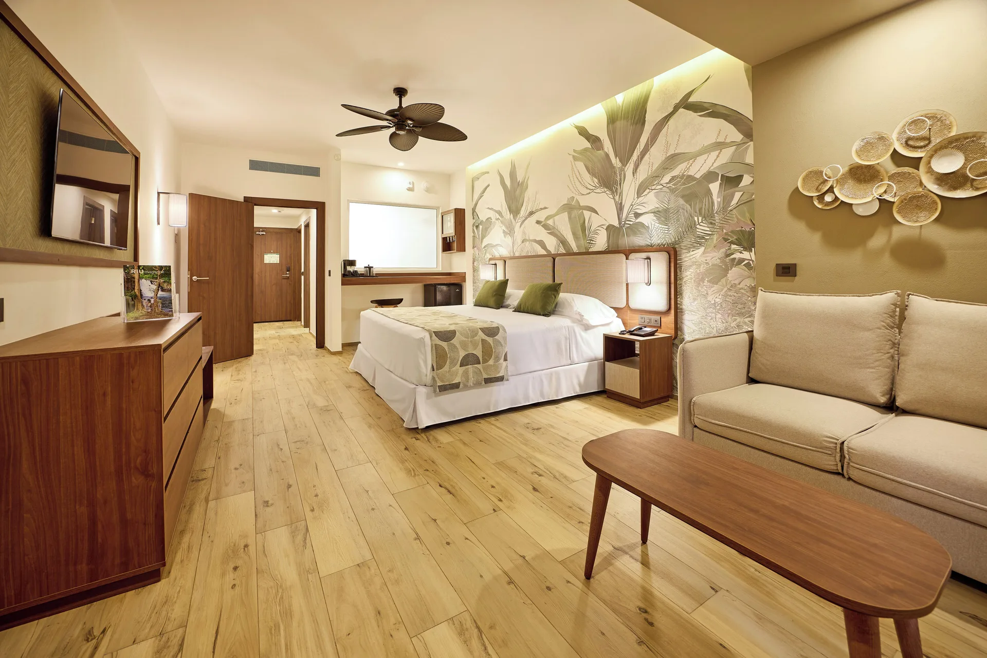 Swim-up adults-only room with bed, sofa, and wood furnishings at Hotel Riu Guanacaste.