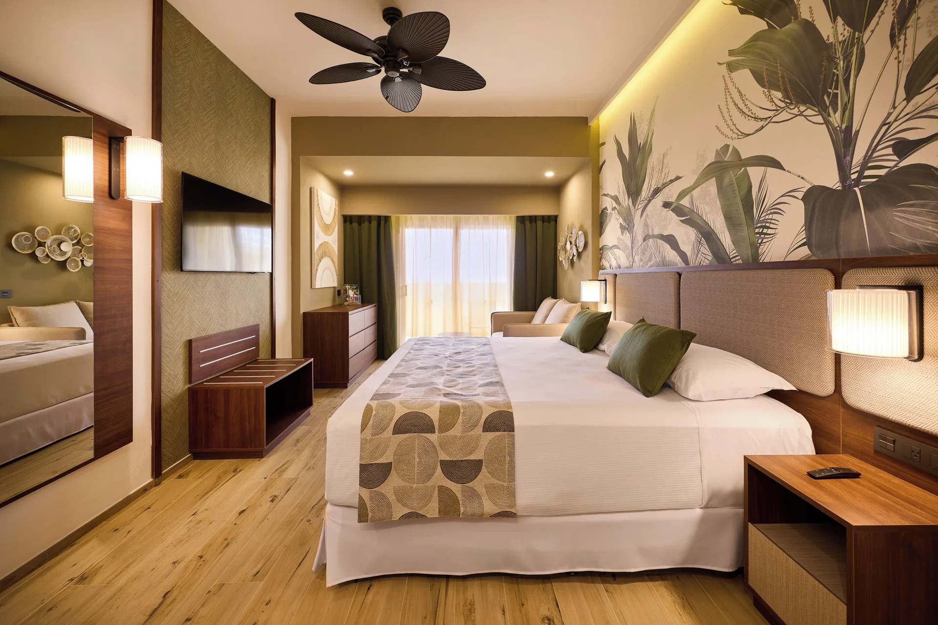 Guest room with king bed, TV, mirror, and balcony doors at Hotel Riu Guanacaste.