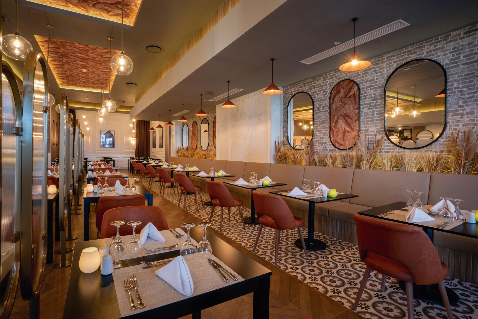 Restaurant dining room with brick wall, mirrors and set tables at Hotel Riu Latino.